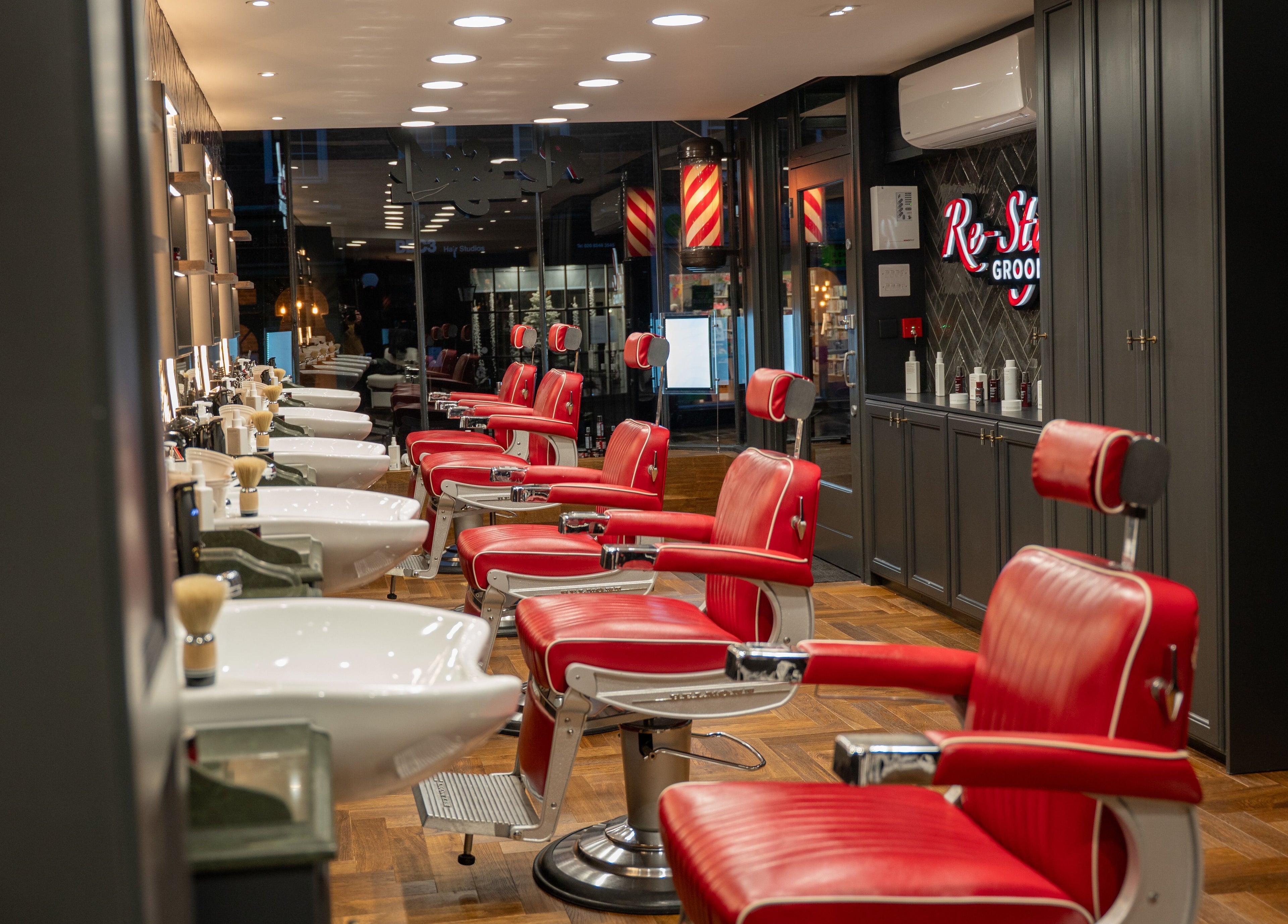 Luxurious red barber chairs at Re-Style Highgate, London, England, GB, showcasing sophisticated grooming space.