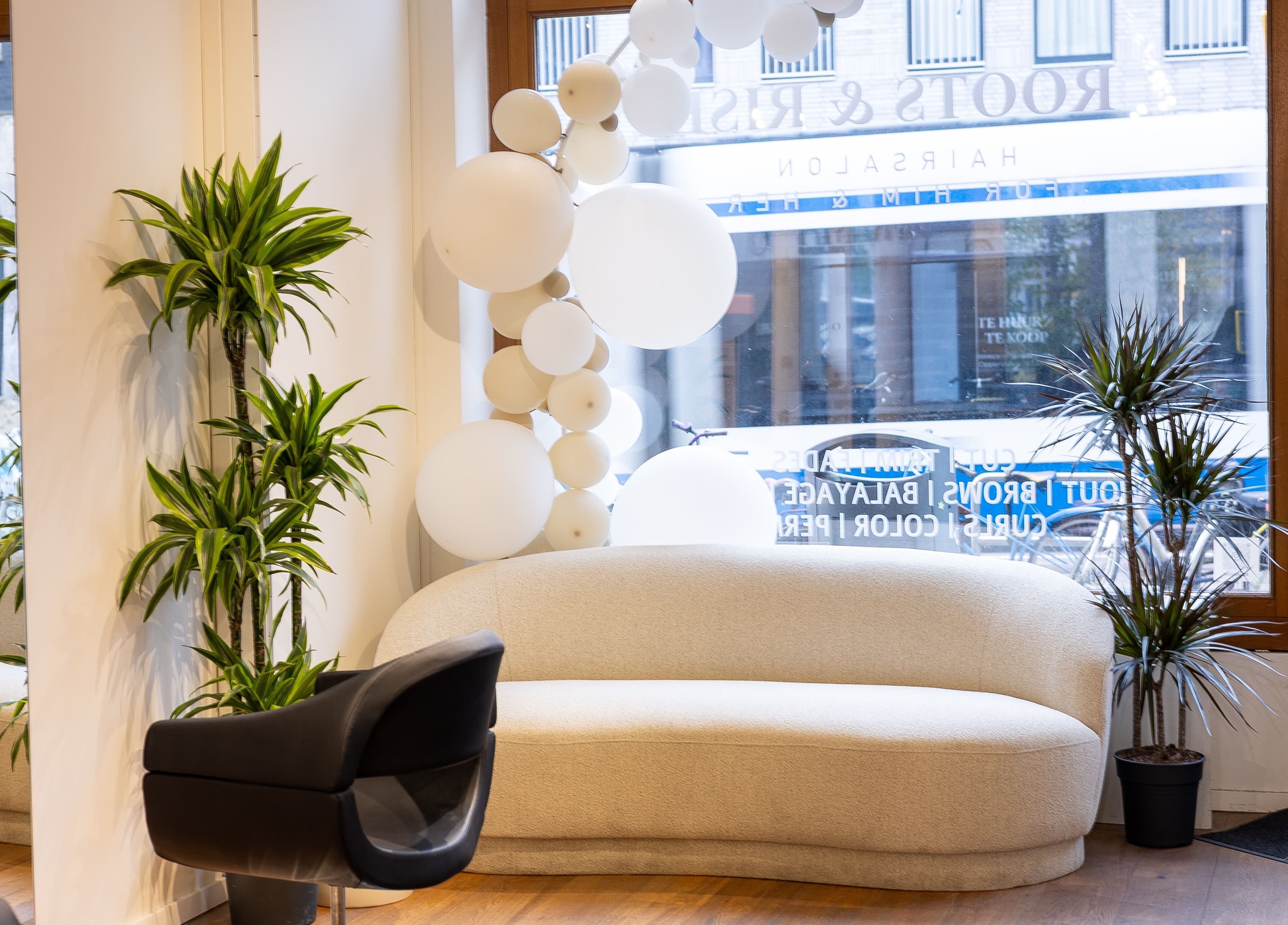 Moderne salonlounge bij HS AMSTERDAM - OOST, Amsterdam, Noord-Holland, NL met witte sofa en groene planten.