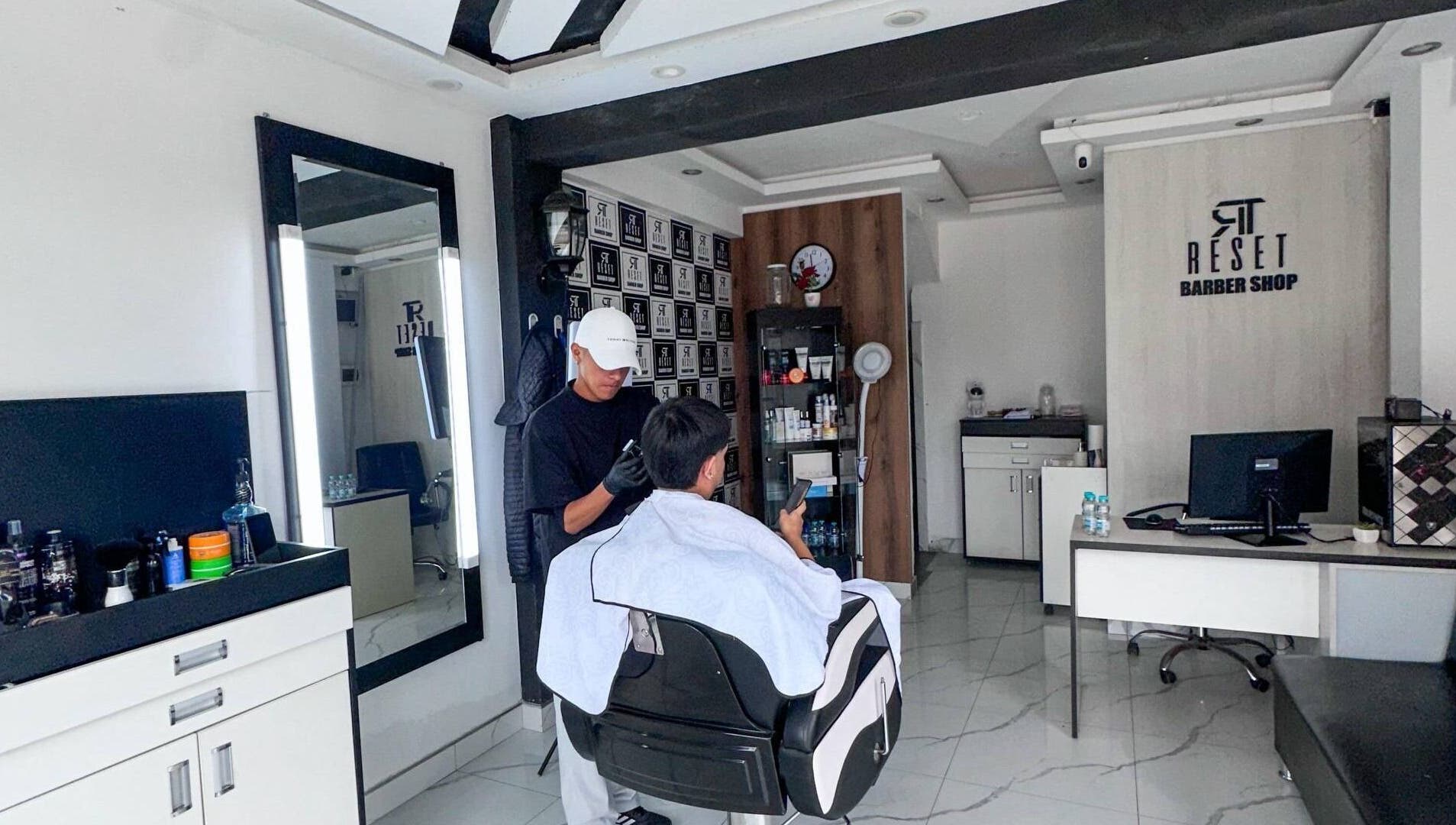 Barbero trabajando cliente en RESET BARBERIA, Ventanilla, Callao, PE, destacando ambiente elegante.