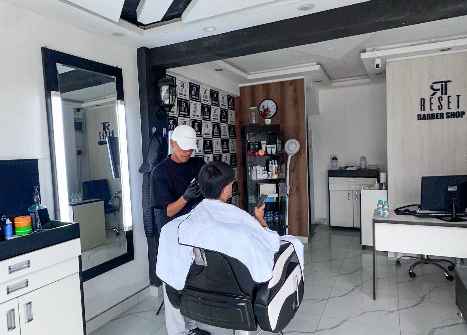 Barbero trabajando cliente en RESET BARBERIA, Ventanilla, Callao, PE, destacando ambiente elegante.