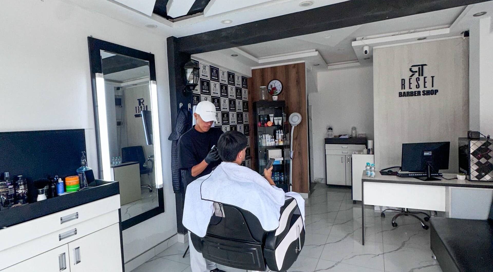 Barbero trabajando cliente en RESET BARBERIA, Ventanilla, Callao, PE, destacando ambiente elegante.