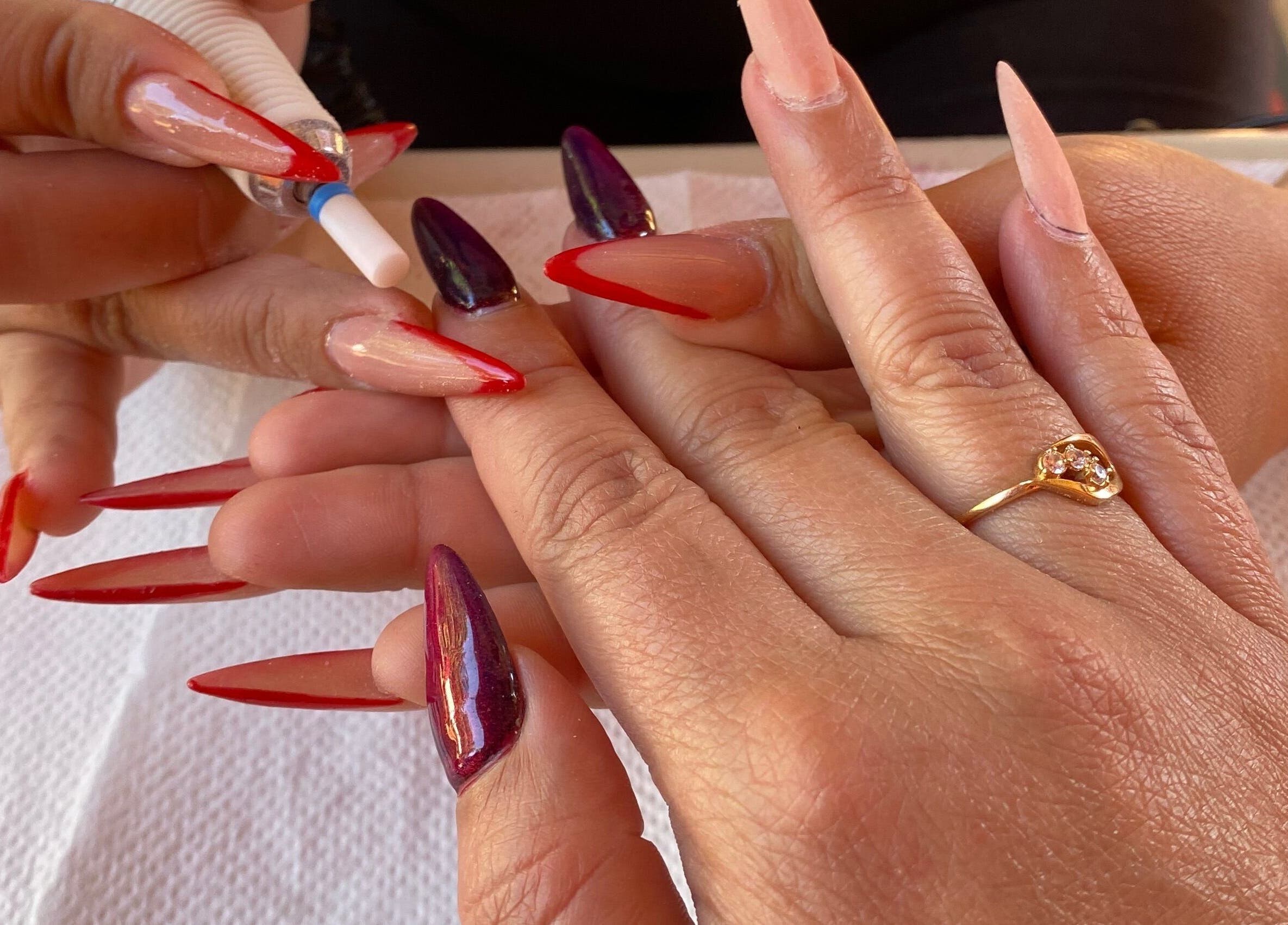 Intricate nail art at Kuarahy Nails Artist in Areguá, Tetãvore Central, PY, featuring red and purple designs.