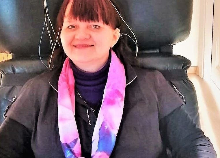 Client enjoying relaxation therapy at RigaBrain, Rīga, LV, seated comfortably with a colorful scarf.