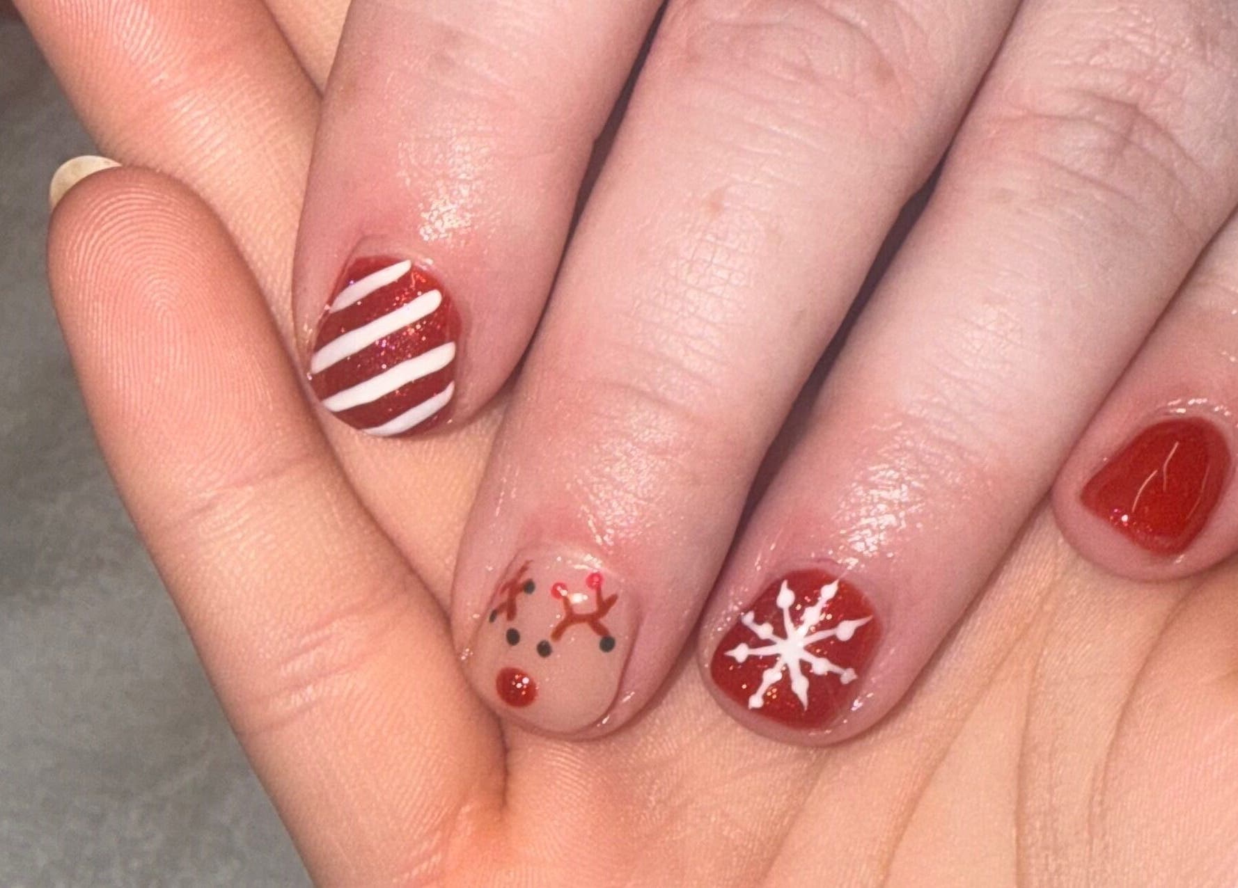 Festive nail art at MK Nails & Beauty in Ballymoney, Northern Ireland, showcasing designs of stripes, reindeer, and snowflakes.
