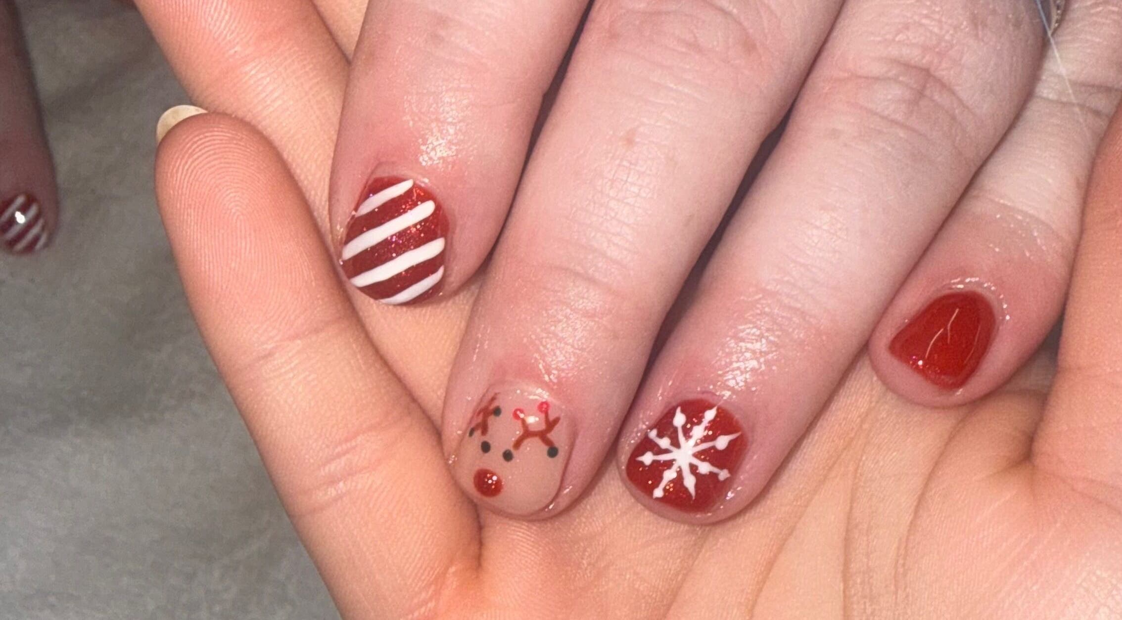 Festive nail art at MK Nails & Beauty in Ballymoney, Northern Ireland, showcasing designs of stripes, reindeer, and snowflakes.