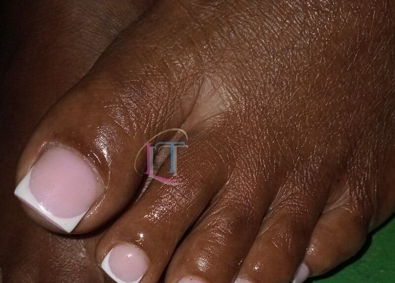 Close-up of a French pedicure at LilysTouch767, Saint David Parish, DM, showcasing glossy, well-groomed nails.
