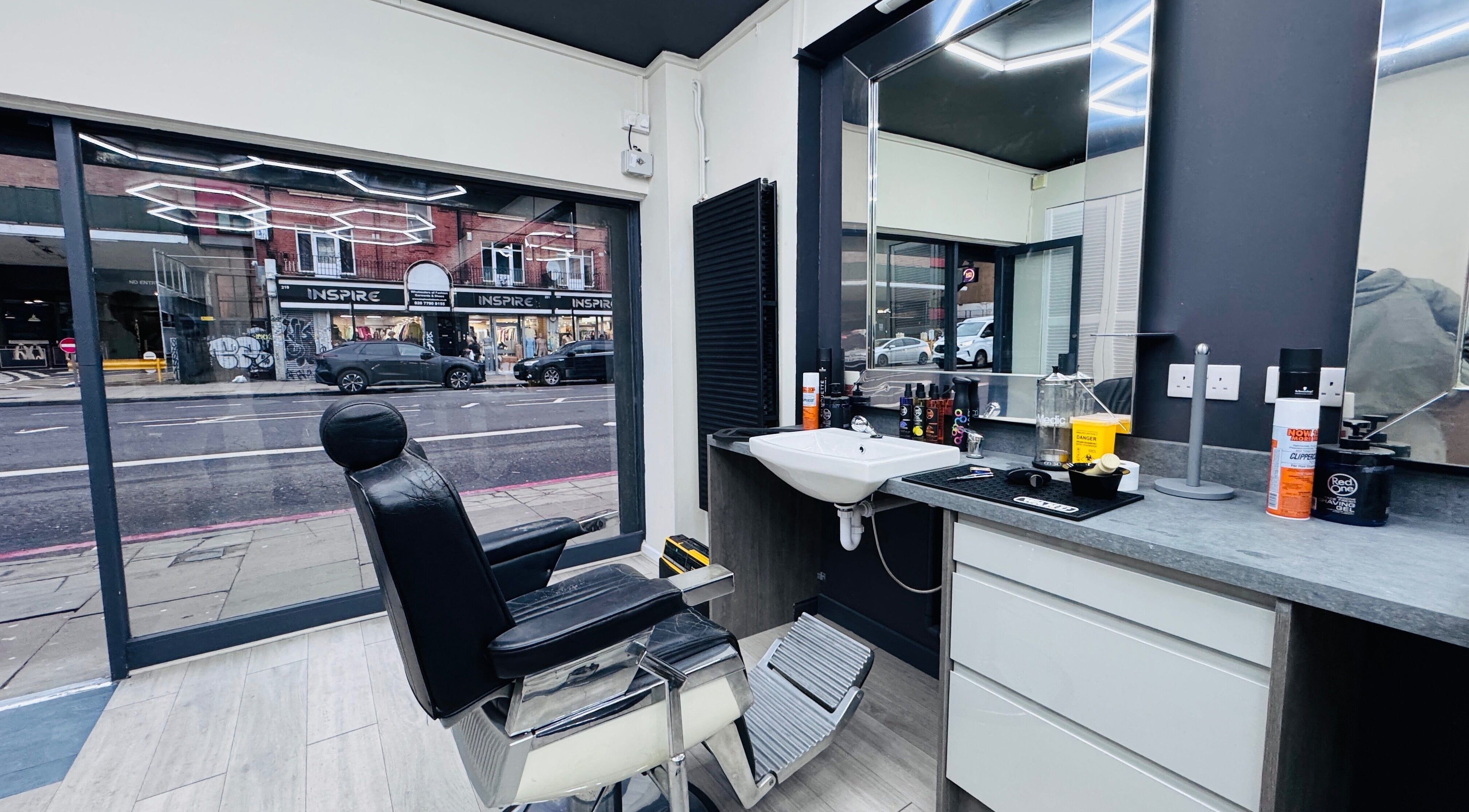 Interior of Danny's Barber in London, England, GB showcasing sleek chair and modern styling area.