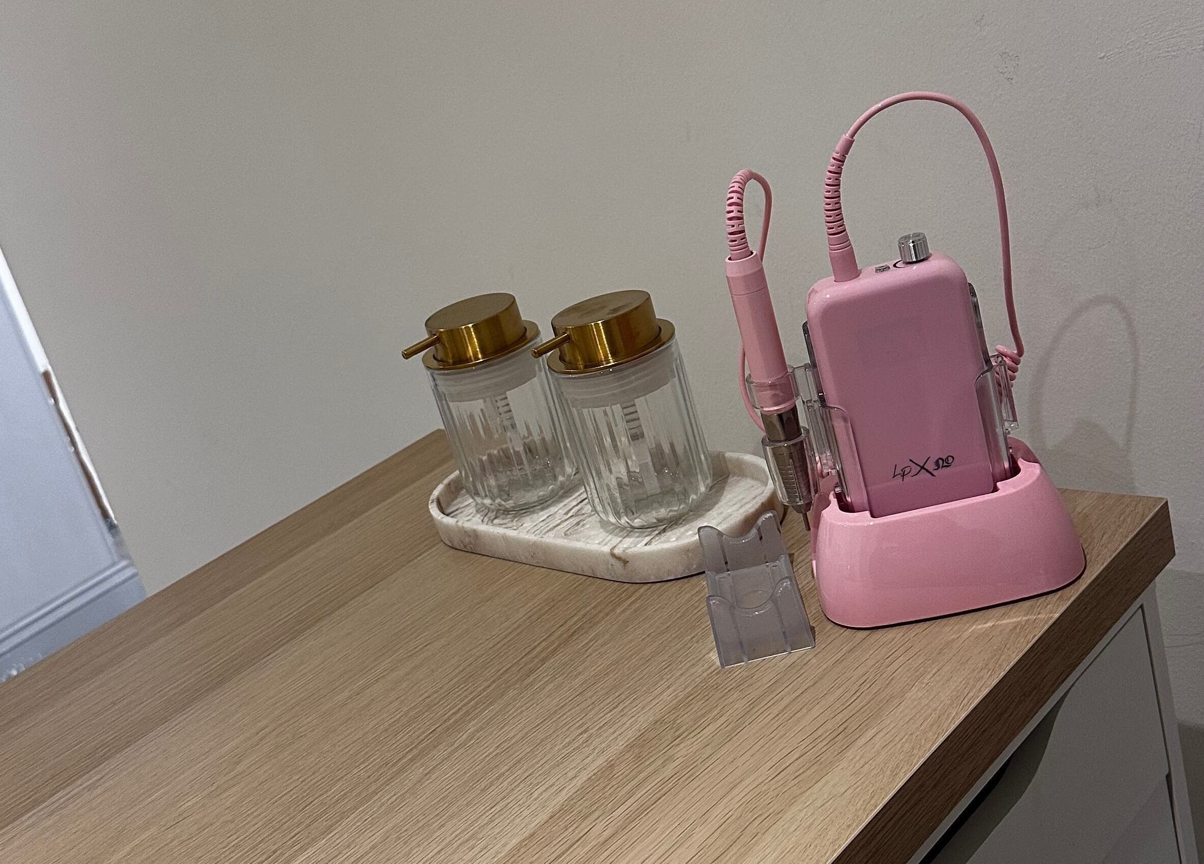 Modern nail equipment at Nails by Mack, Lanark, Scotland, GB, featuring pink drill and stylish jars.