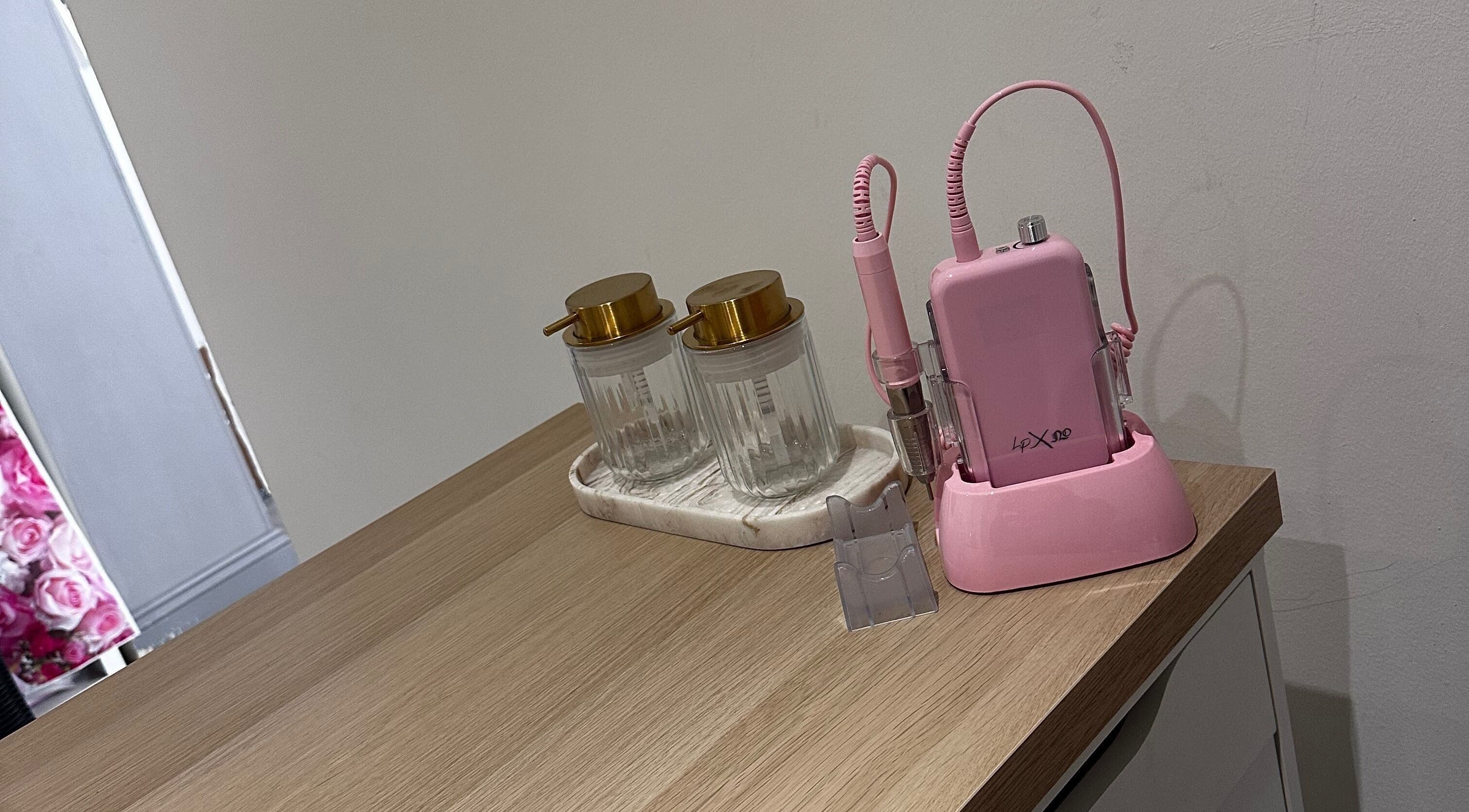 Modern nail equipment at Nails by Mack, Lanark, Scotland, GB, featuring pink drill and stylish jars.