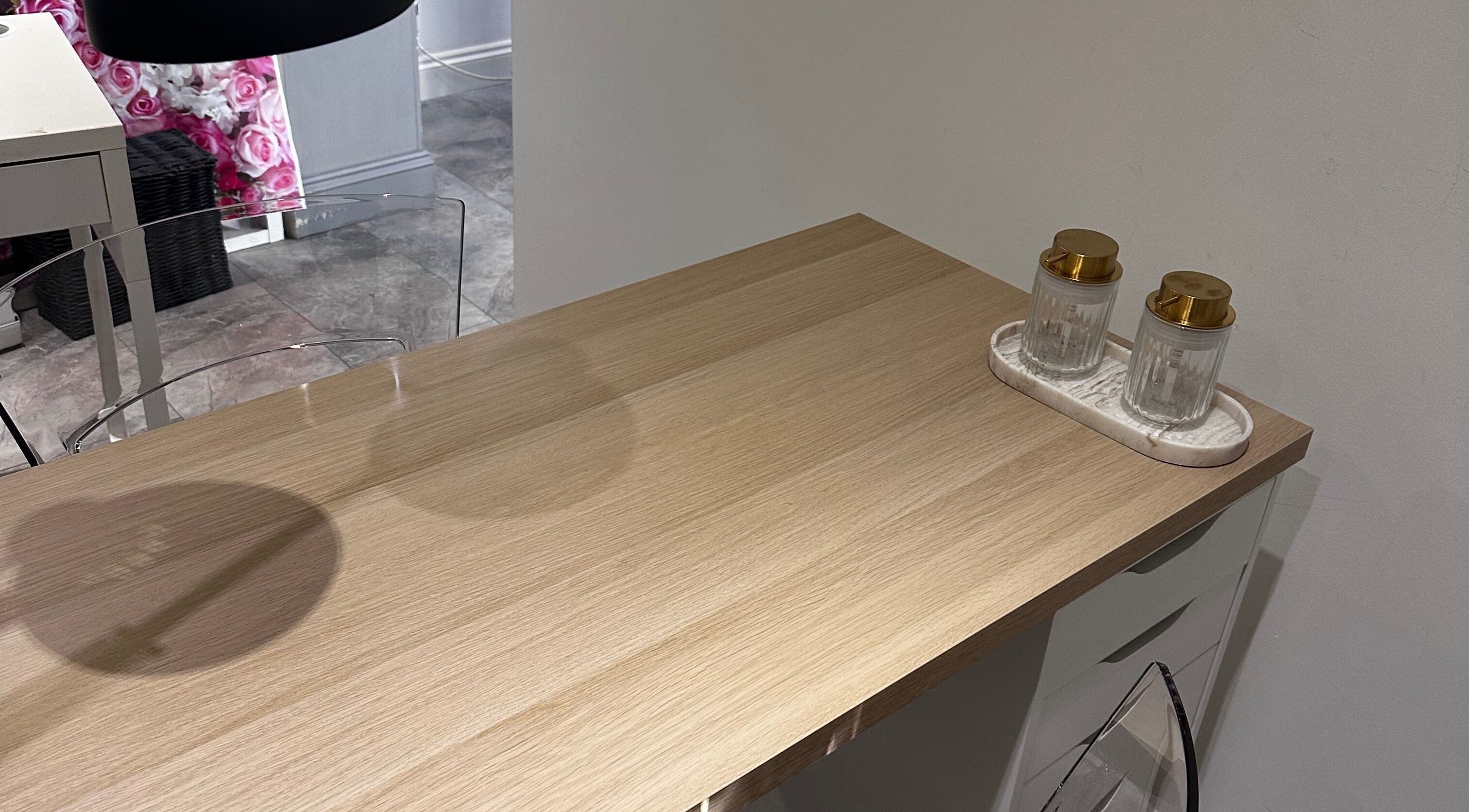 Sleek wooden nail table at Nails by Mack in Lanark, Scotland, GB, with two decorative jars.