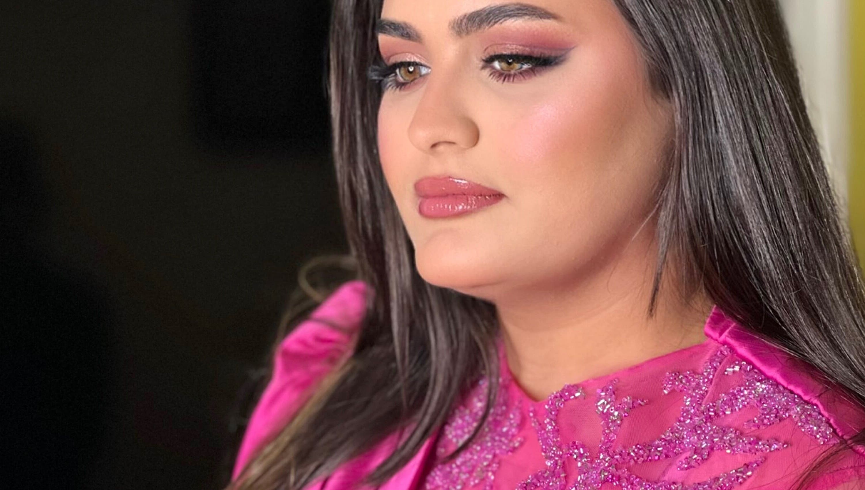 Woman in glamorous pink attire at Glam by Sara, Harrisburg, Pennsylvania, US, showcasing vibrant makeup.