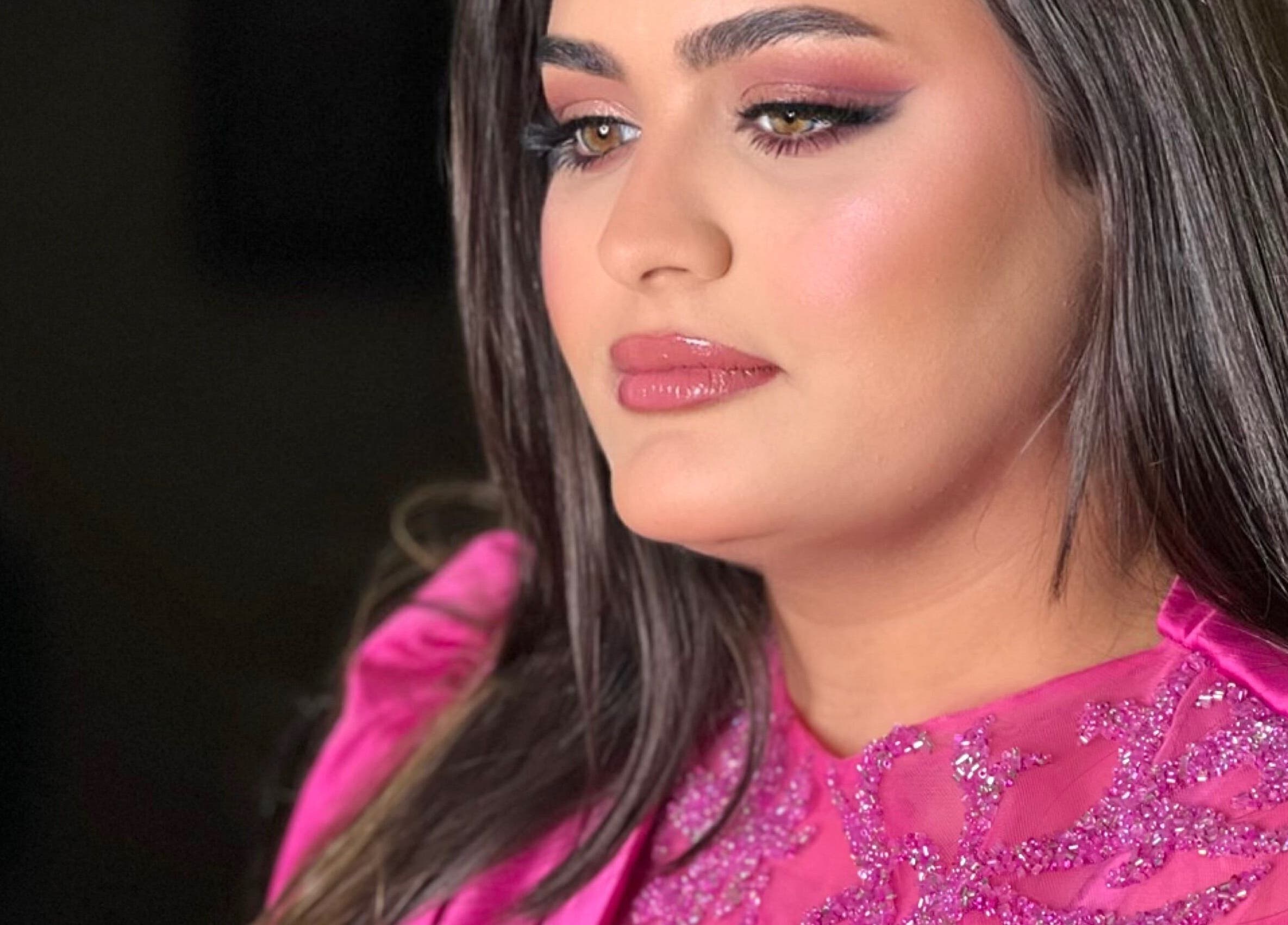 Woman in glamorous pink attire at Glam by Sara, Harrisburg, Pennsylvania, US, showcasing vibrant makeup.