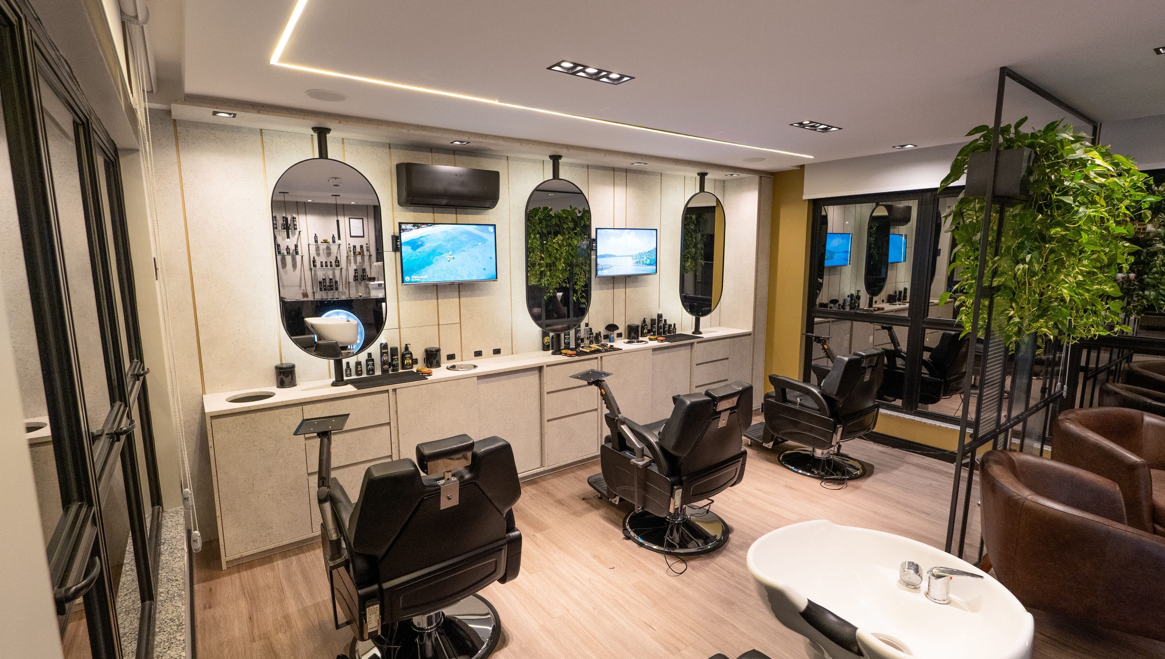 Interior moderno da Forum Barbearia em Santa Catarina, Santa Catarina, BR, com assentos confortáveis e TVs.