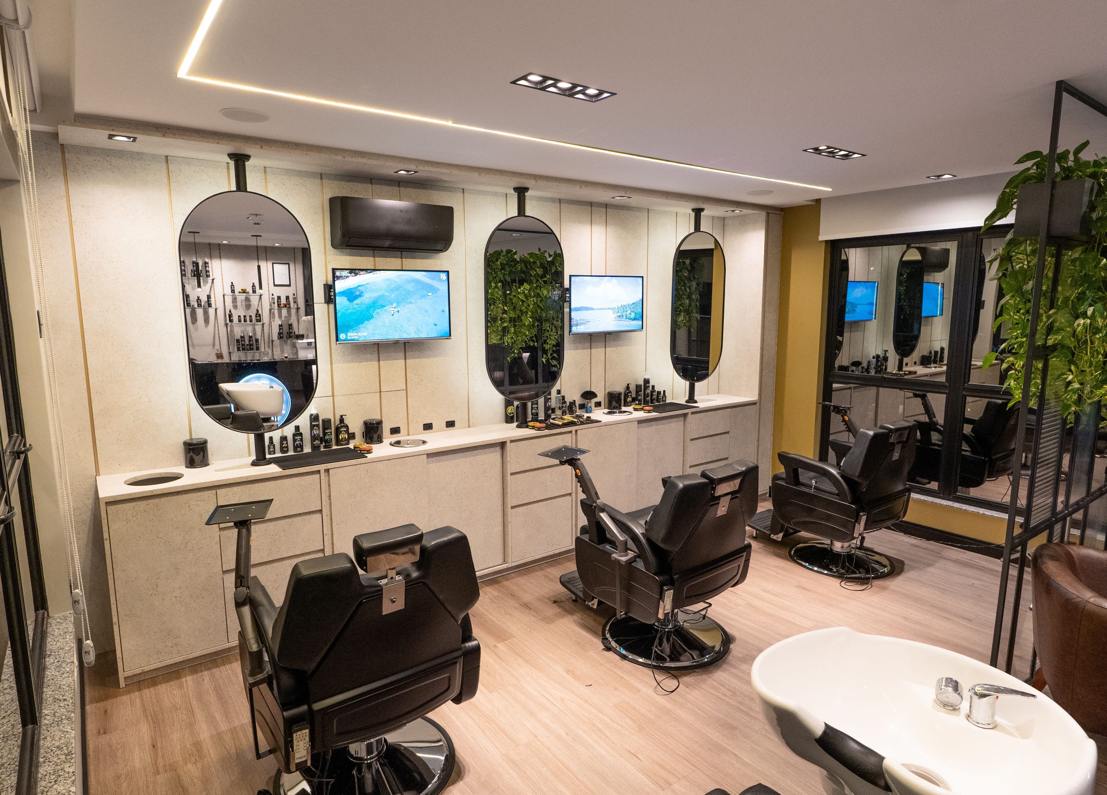 Interior moderno da Forum Barbearia em Santa Catarina, Santa Catarina, BR, com assentos confortáveis e TVs.