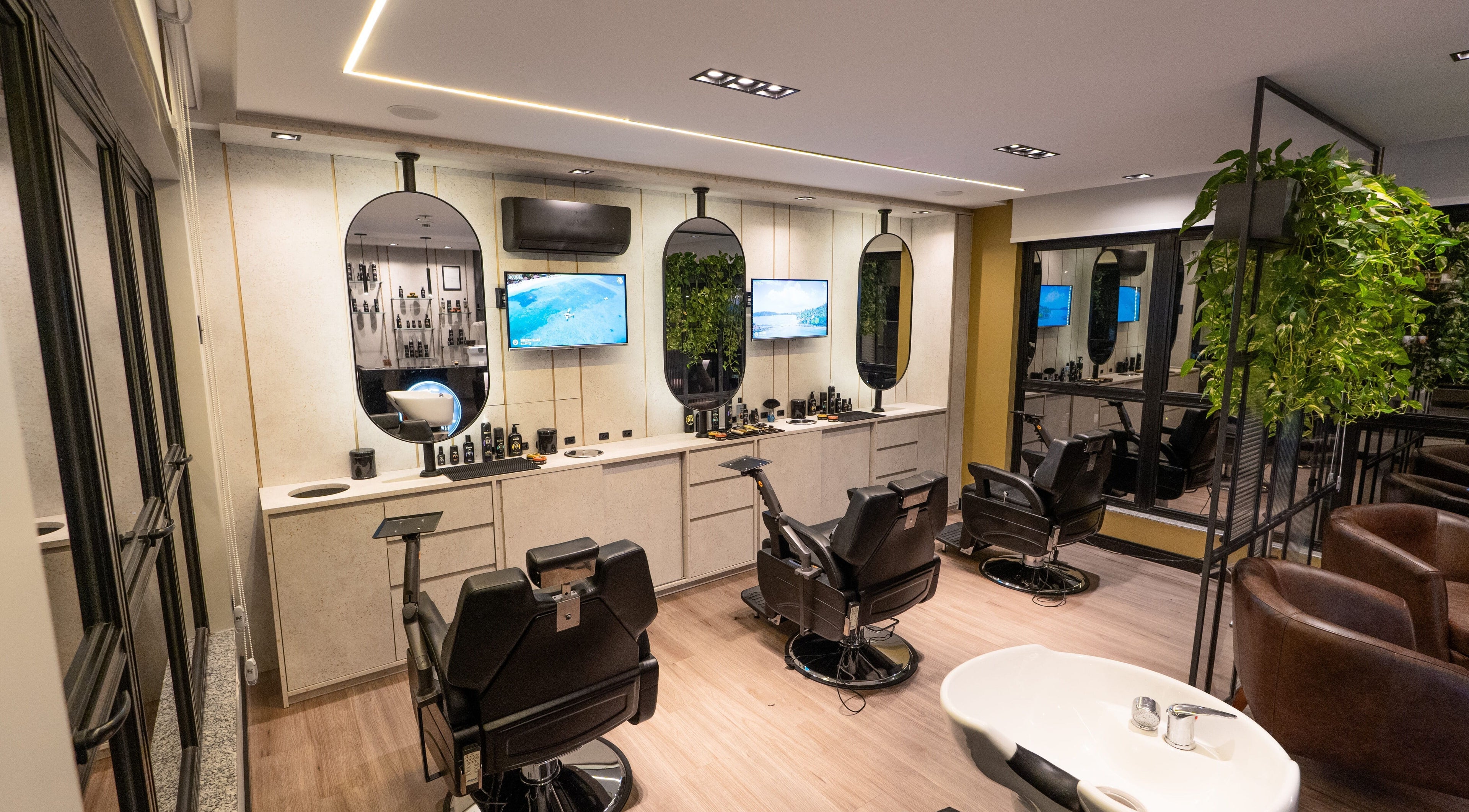 Interior moderno da Forum Barbearia em Santa Catarina, Santa Catarina, BR, com assentos confortáveis e TVs.