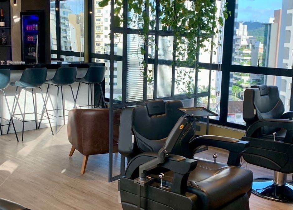 Interiores modernos do Forum Barbearia em Santa Catarina, BR, com cadeiras sofisticadas e bar acolhedor.