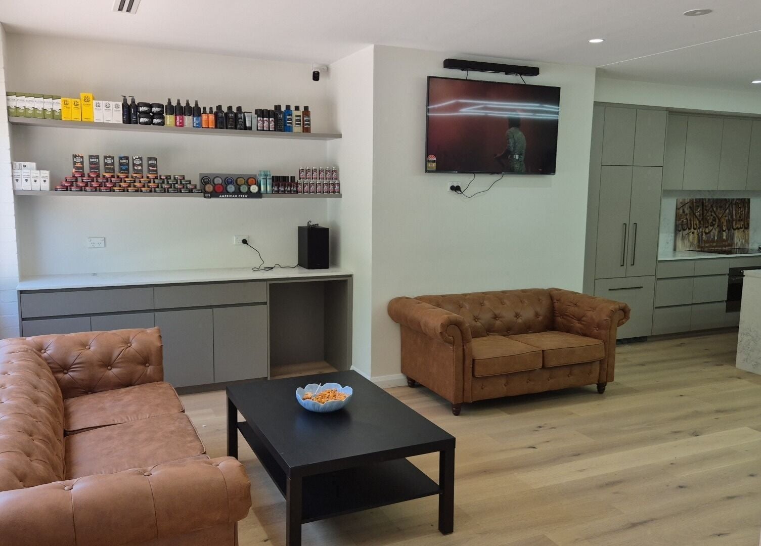 Cozy lounge area in THE MANUAL BARBER, Braddon, Australian Capital Territory, features leather sofas and shelving.