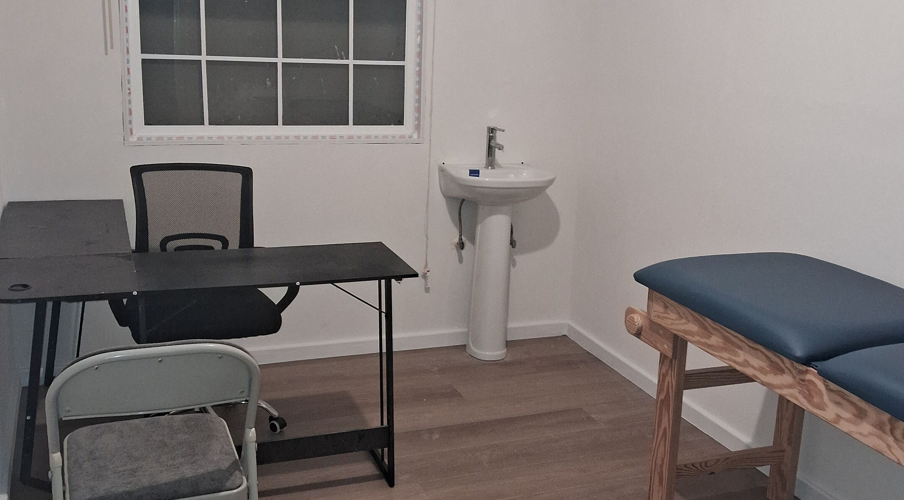 Consultation room at Dolizanel Medical, Oistins, Christ Church, featuring desk and examination table.