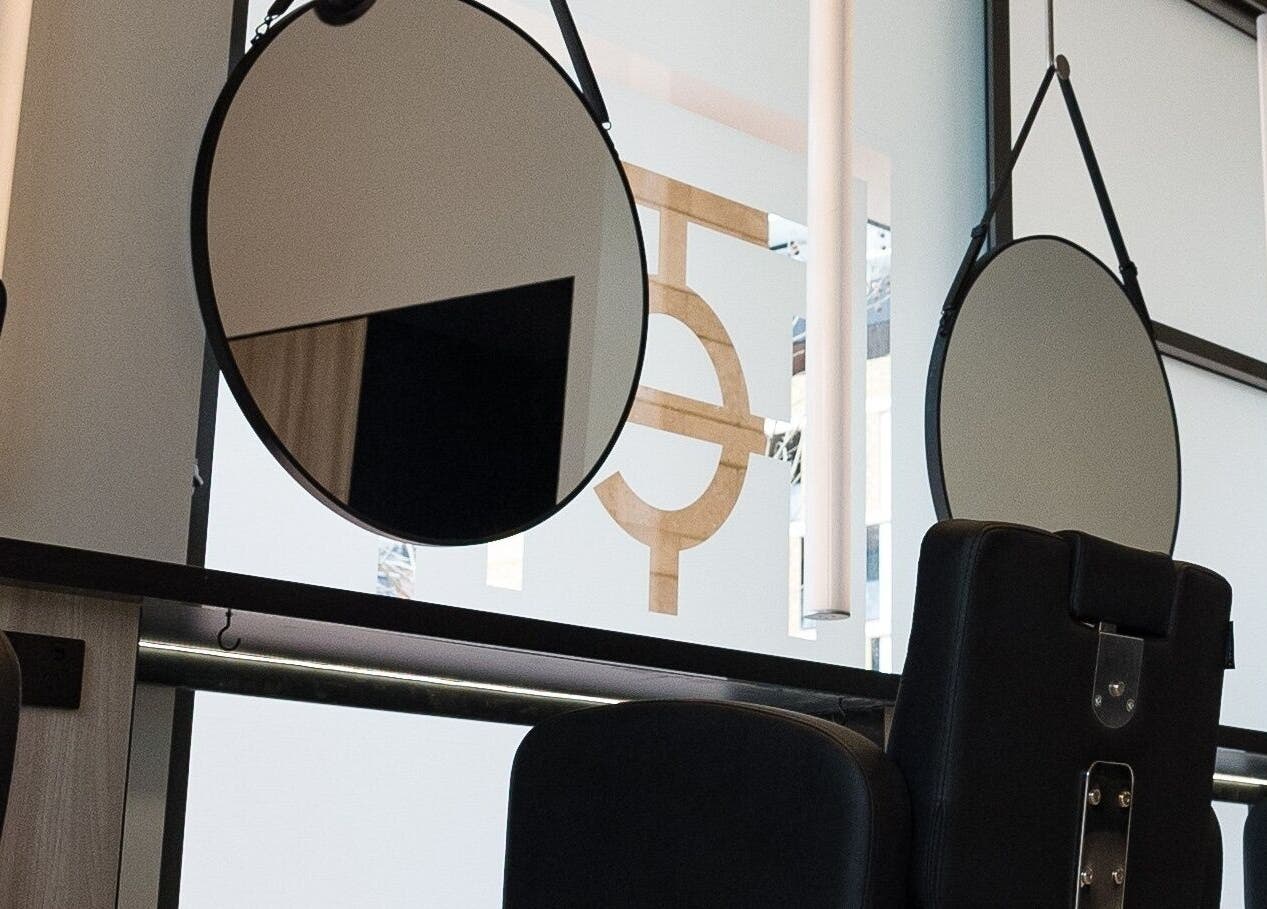 Modern salon stations at Yasu in Perth, Western Australia, AU, featuring sleek black chairs and round mirrors.