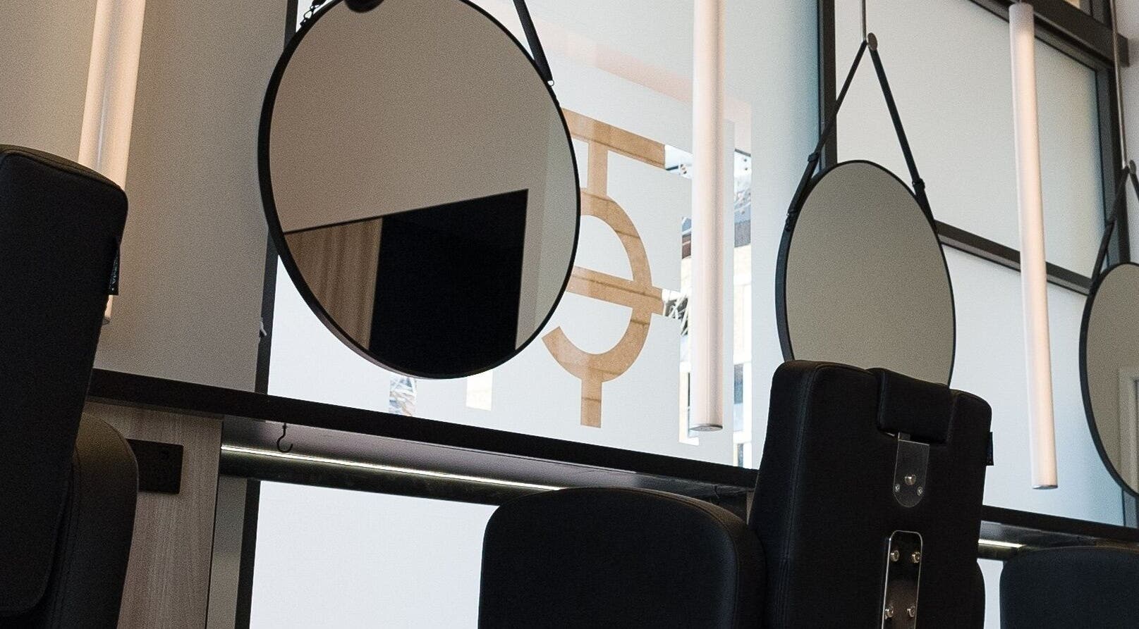 Modern salon stations at Yasu in Perth, Western Australia, AU, featuring sleek black chairs and round mirrors.