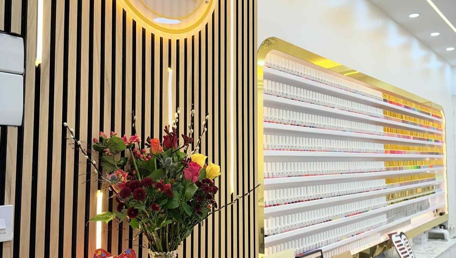 Amber Glow Nails & Beauty in London, England, GB features an elegant nail polish display and floral arrangement.