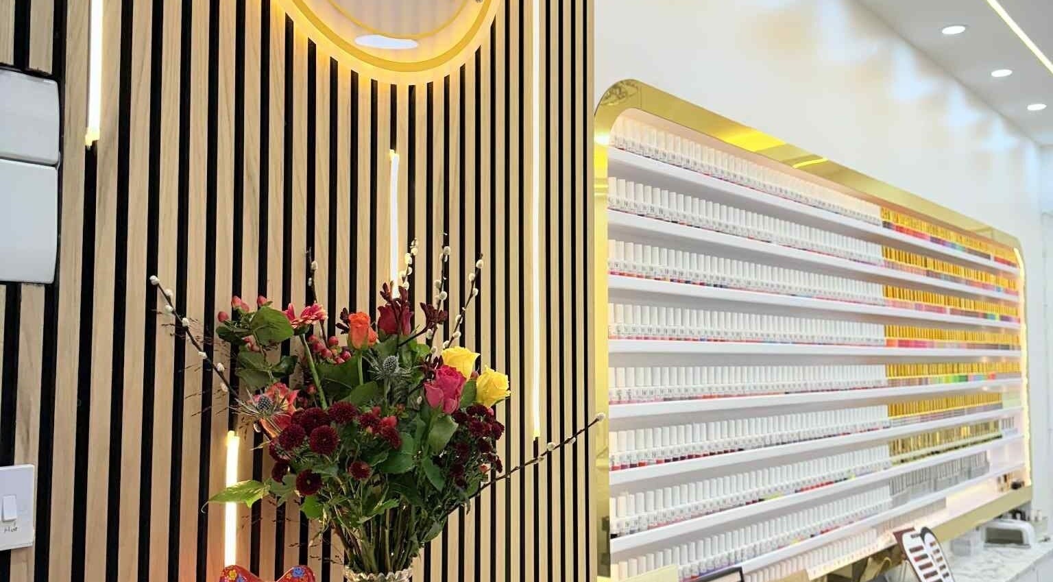 Amber Glow Nails & Beauty in London, England, GB features an elegant nail polish display and floral arrangement.