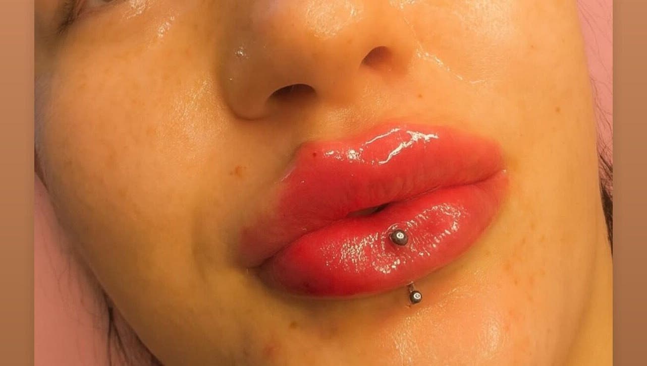 Close-up of glossy lips with piercing at Doll Faced beauty venue, GB.
