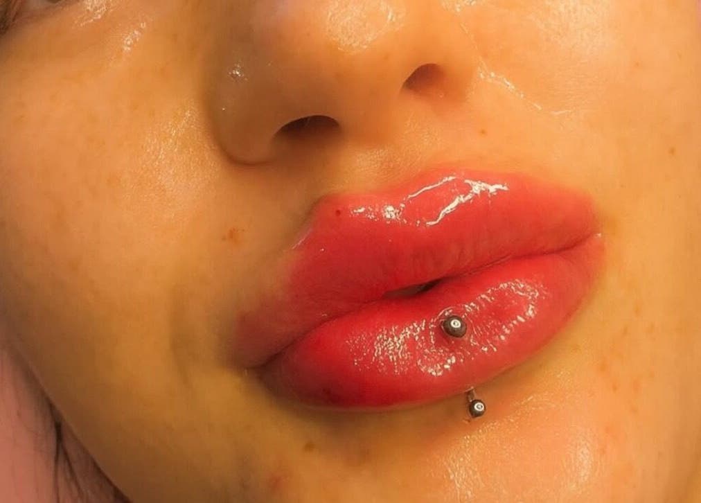 Close-up of glossy lips with piercing at Doll Faced beauty venue, GB.