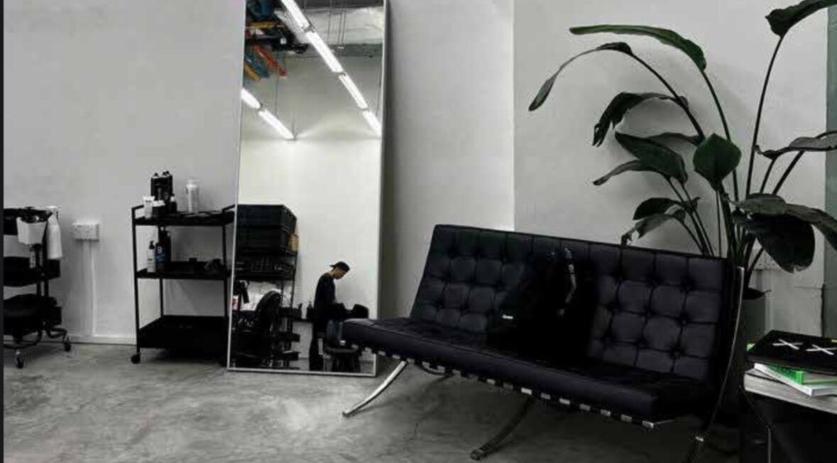 Interno elegante di MENSTUDIO a Viganello, Ticino, CH con specchio e divano moderno.