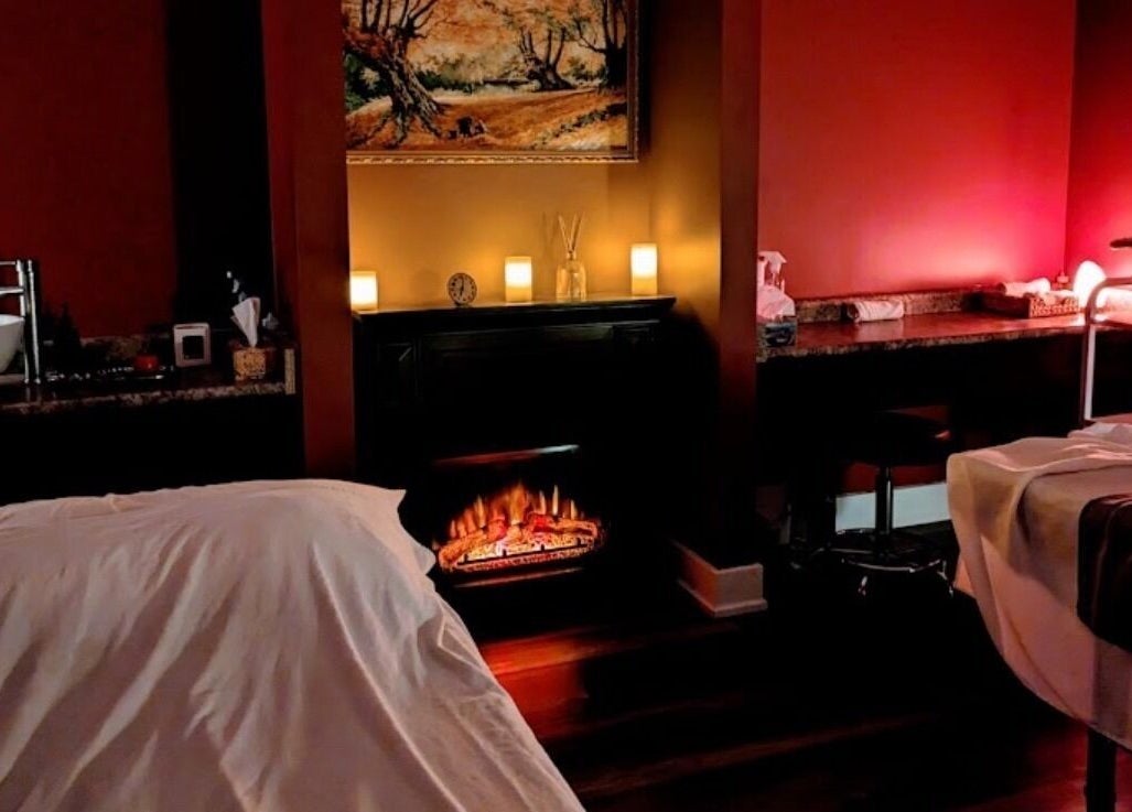 Relaxing massage room at Exhale Spa and WellnessElite, Toronto, Ontario, CA with ambient lighting and fireplace.