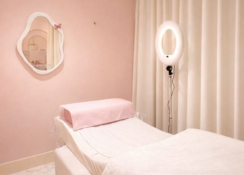 Peaceful treatment room at Dinivé Beauty in London, England, GB, with soft pink decor and a treatment bed.