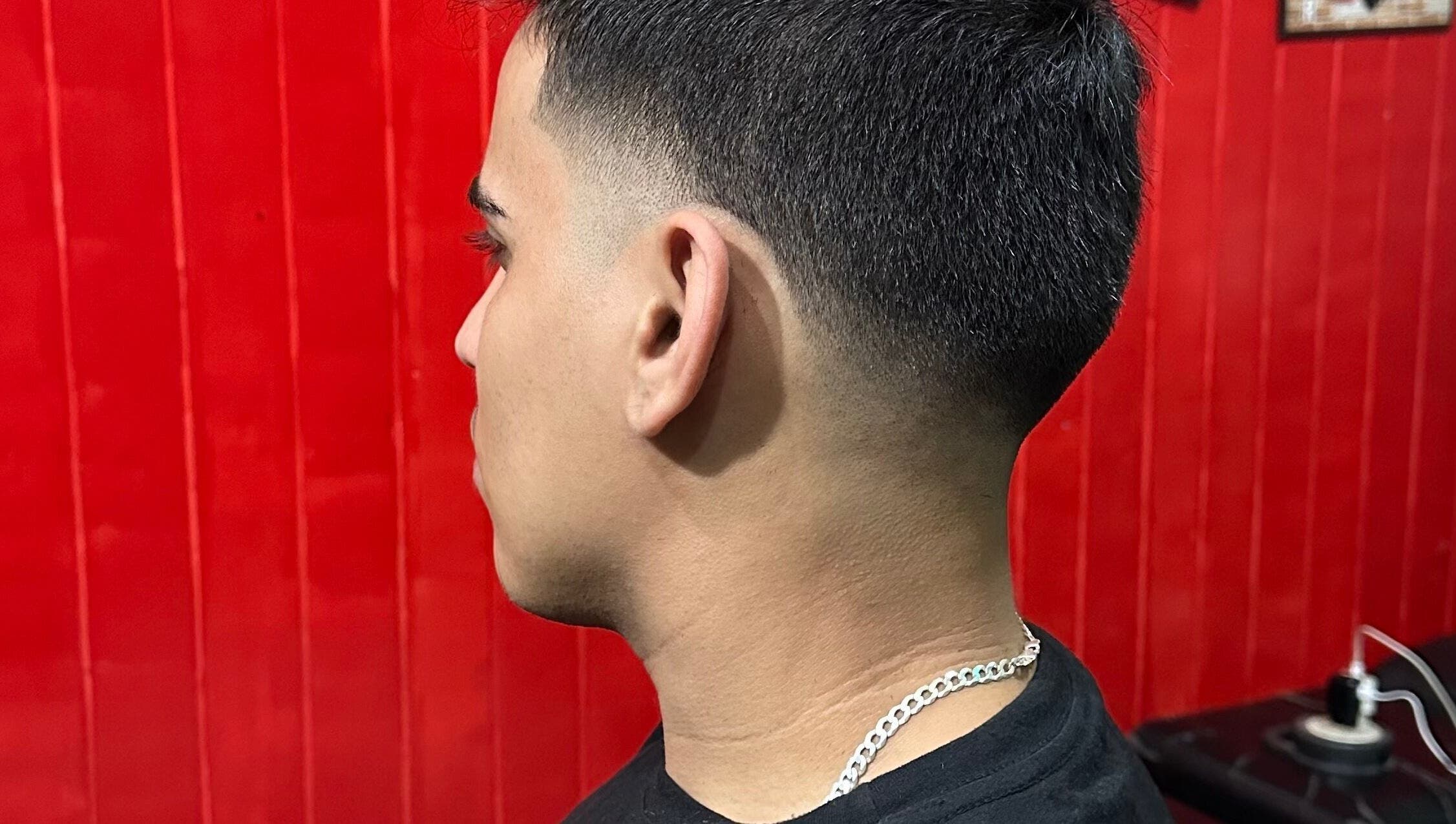Corte de cabelo ajustado em Thiago Barber, Ceará, Ceará, BR, com fundo vermelho realçando o corte.