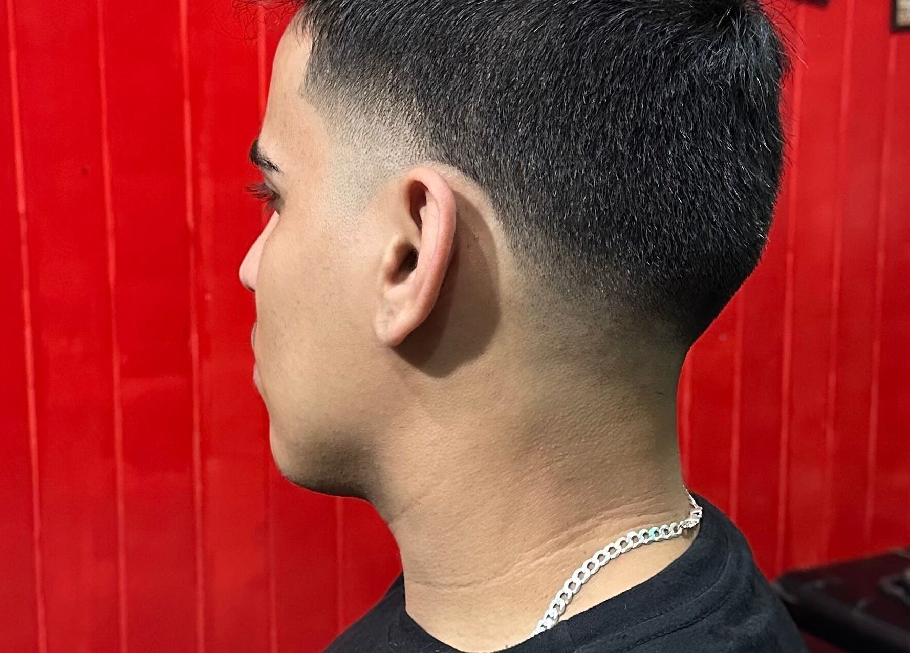 Corte de cabelo ajustado em Thiago Barber, Ceará, Ceará, BR, com fundo vermelho realçando o corte.