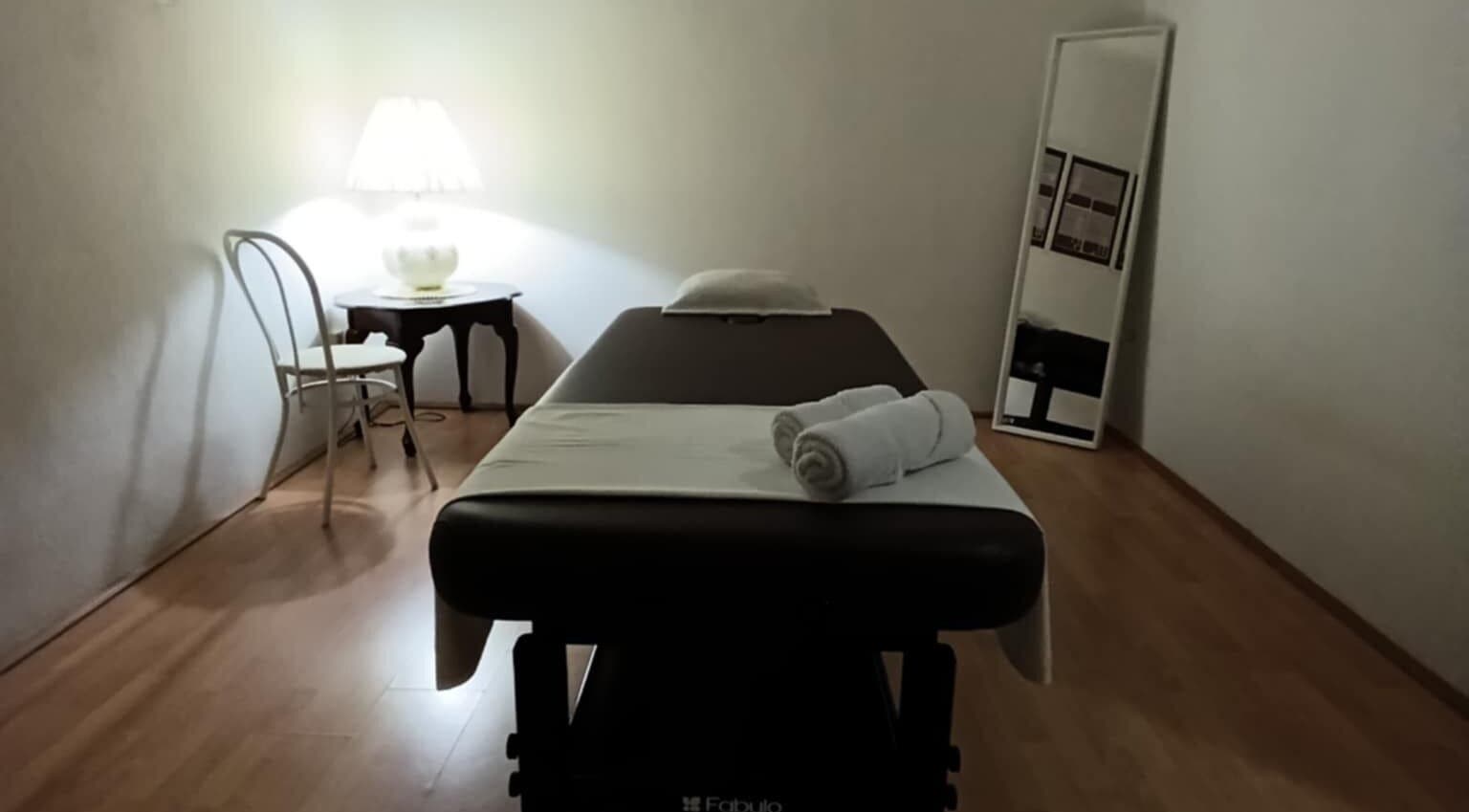 Cozy massage room at ONE Thai Solution Massage, Budapest, Magyar, HU with a lit lamp and comfortable table.