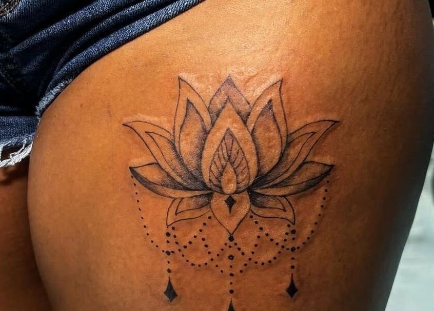 Elegant lotus tattoo design on thigh at TaintedTats, Charlotte, North Carolina, US offers unique body art.