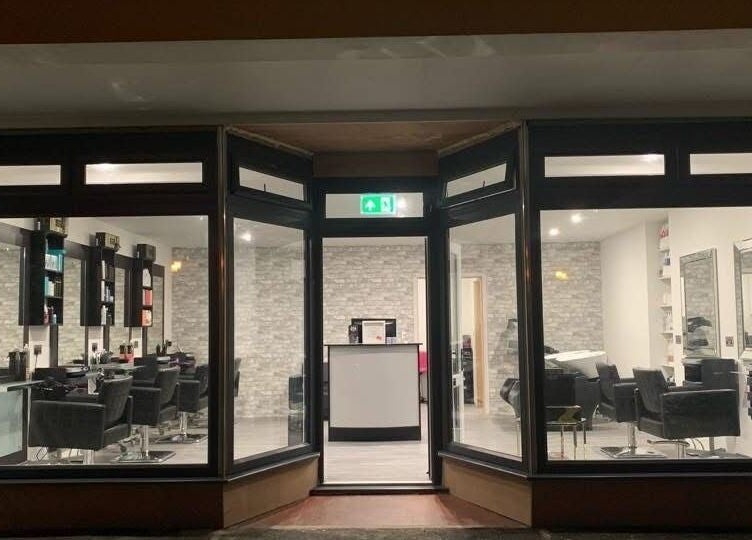 Night view of Hair By Jen, Jersey, St Saviour, JE showcasing stylish salon chairs and mirrors.