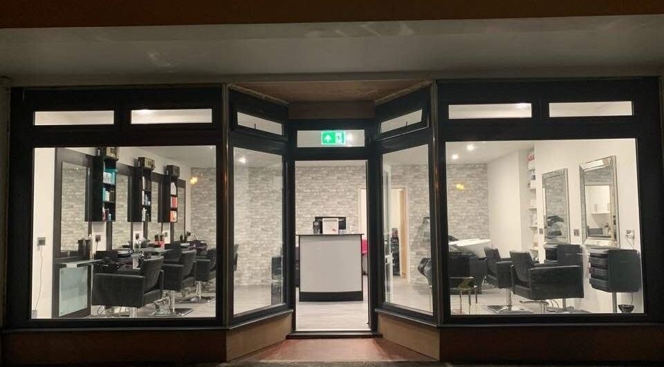 Night view of Hair By Jen, Jersey, St Saviour, JE showcasing stylish salon chairs and mirrors.