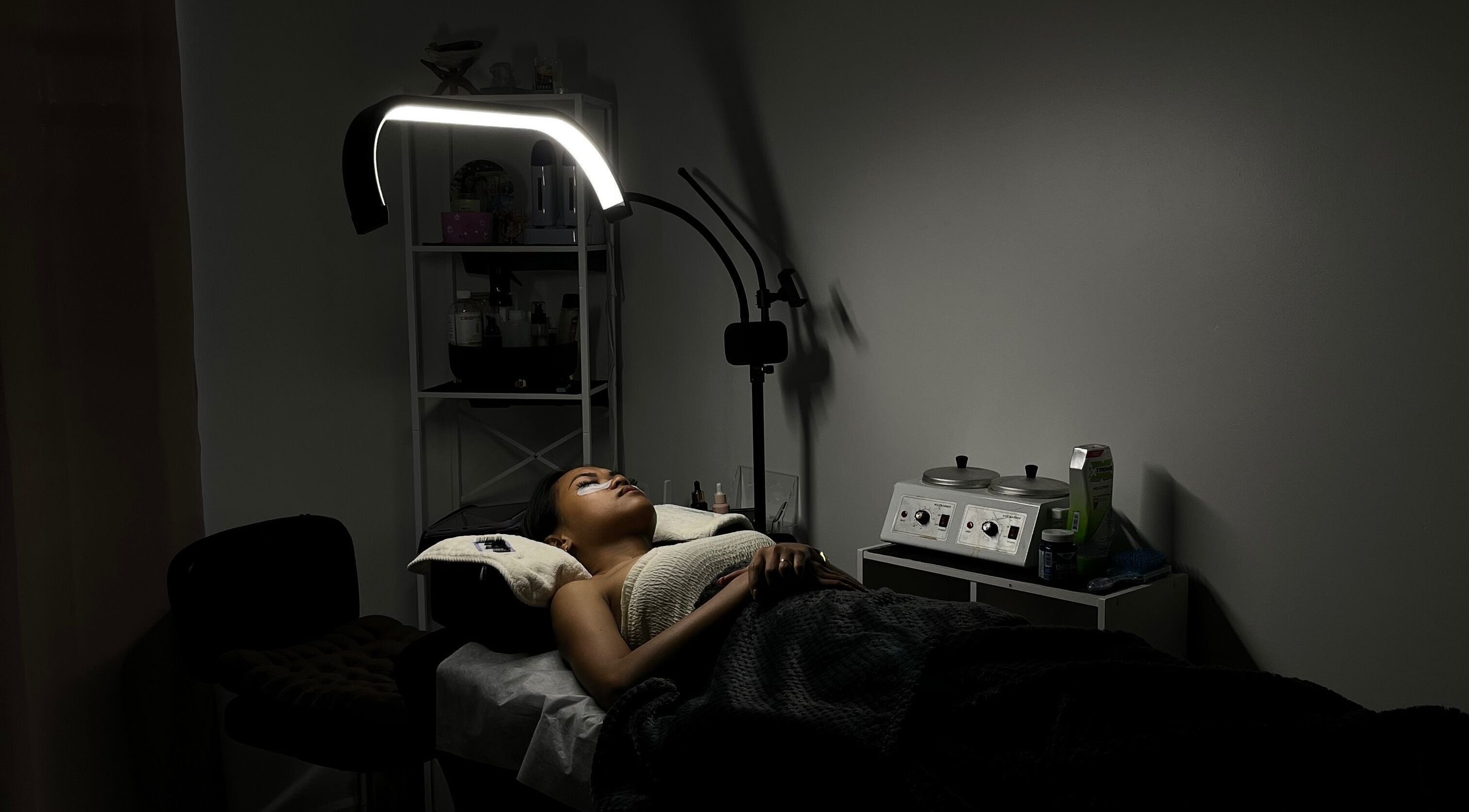 Serene treatment room at POISE BEAUTY, Paramaribo, SR, showcasing a client enjoying a spa session under soft lighting.