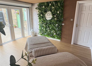 Relaxing therapy room at The Retreat, Barnsley, England, GB, with massage table, greenery wall, and natural light.