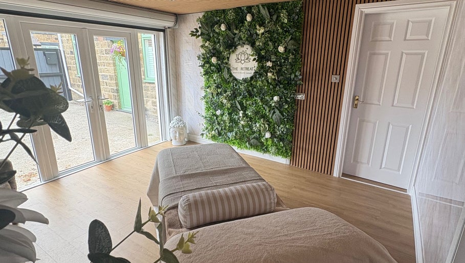 Tranquil therapy room at The Retreat in Barnsley, England, GB featuring a massage bed and lush green decor.