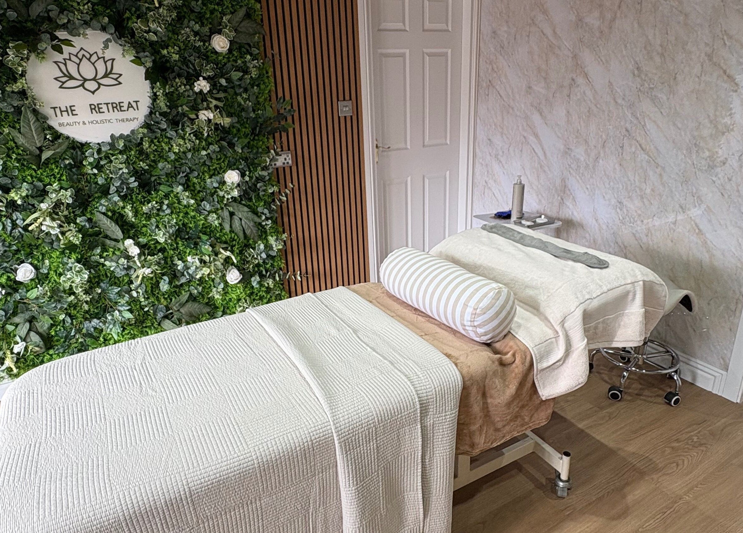 Tranquil treatment room at The Retreat, Barnsley, England, GB, featuring a cozy massage bed and lush greenery.