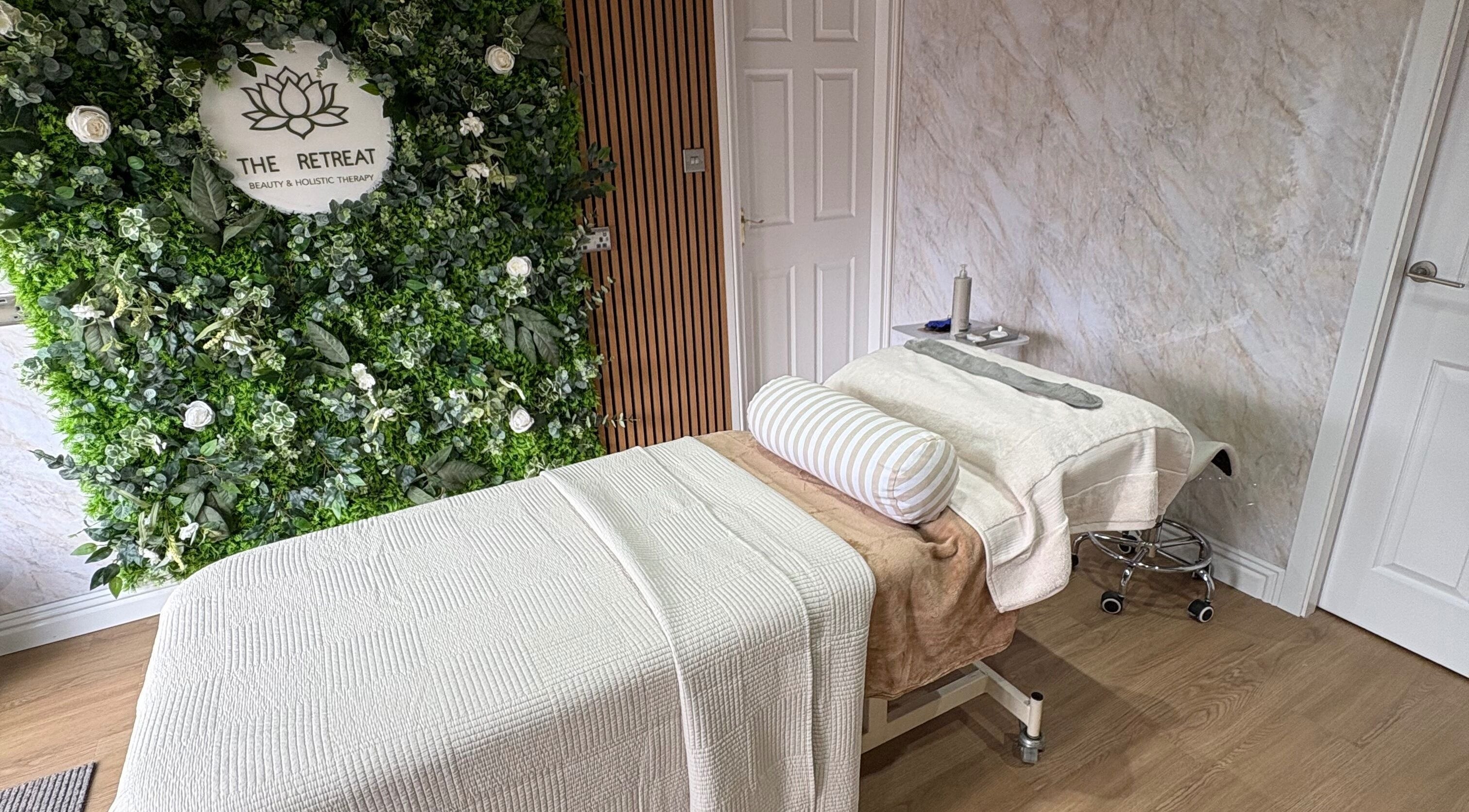 Tranquil treatment room at The Retreat, Barnsley, England, GB, featuring a cozy massage bed and lush greenery.