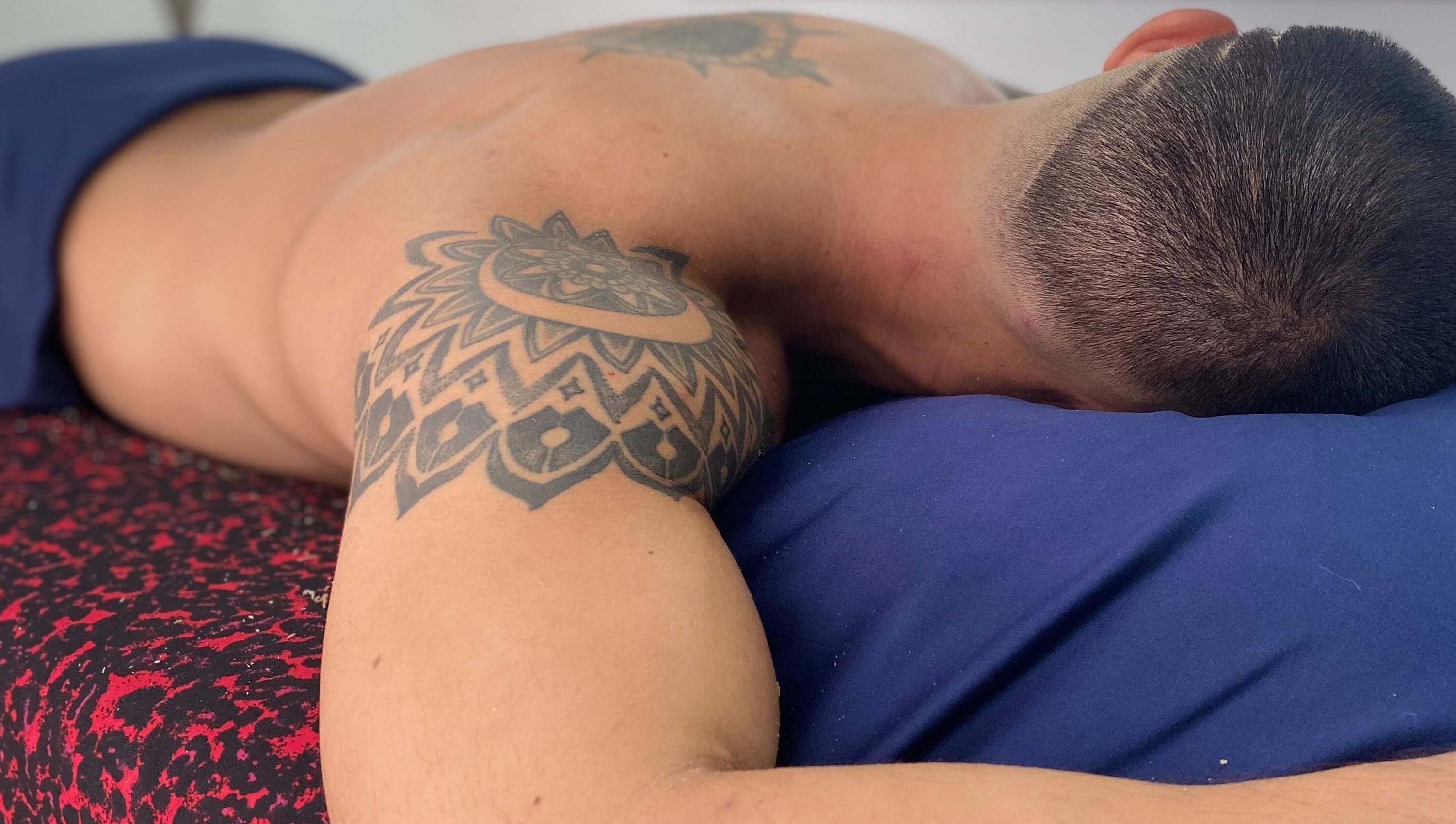 Relajación en andoconestilo, Mérida, Yucatán, MX. Cliente disfrutando masaje relajante con tatuajes visibles.