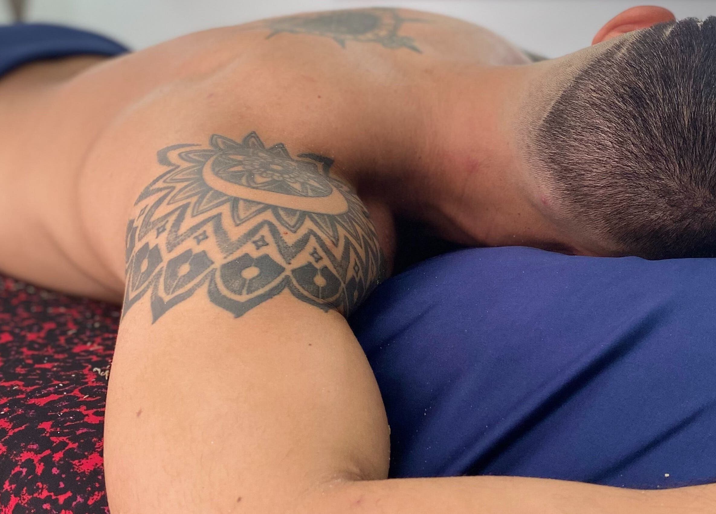 Relajación en andoconestilo, Mérida, Yucatán, MX. Cliente disfrutando masaje relajante con tatuajes visibles.