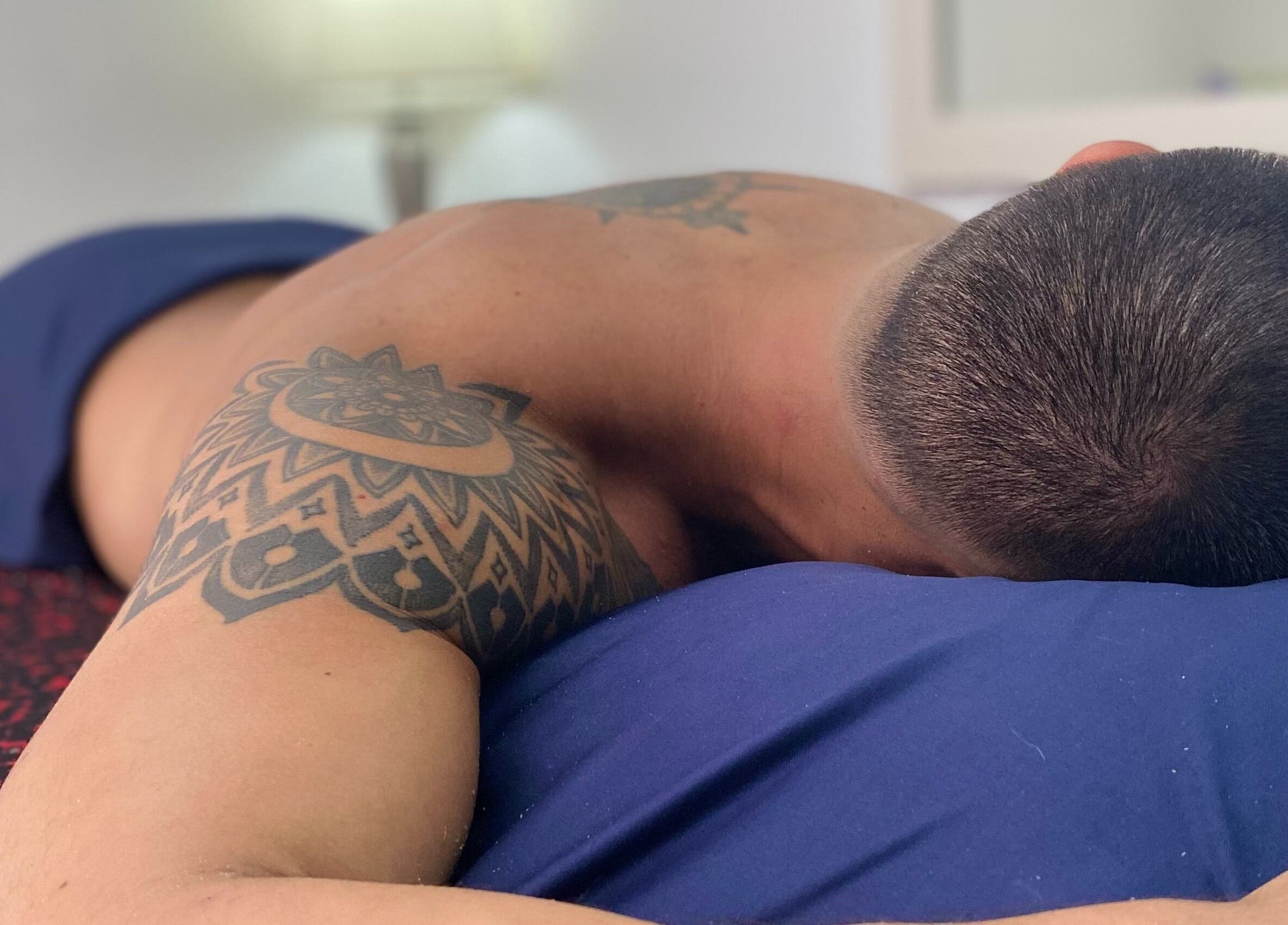 Sesión de masaje relajante en andoconestilo, Mérida, Yucatán, MX. Hombre con tatuaje en la espalda descansando.