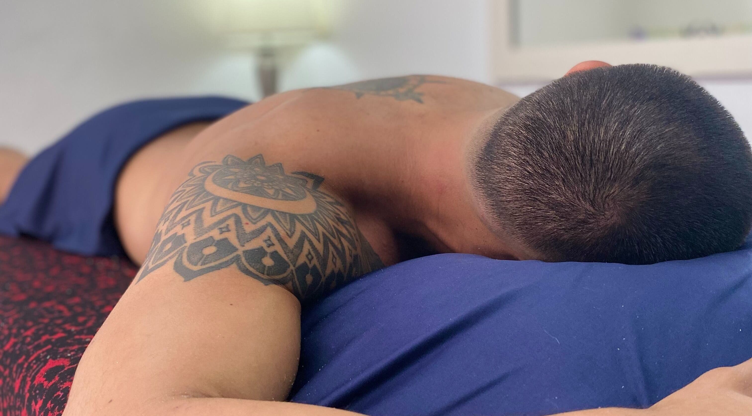 Sesión de masaje relajante en andoconestilo, Mérida, Yucatán, MX. Hombre con tatuaje en la espalda descansando.