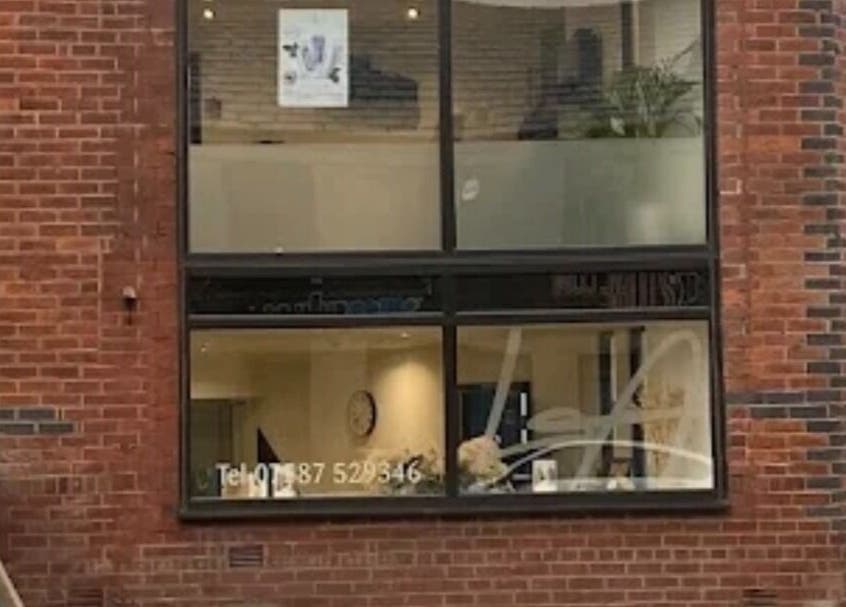 Front facade of The Toni Touch beauty salon in Bolton, England, GB with large windows and brick exterior.