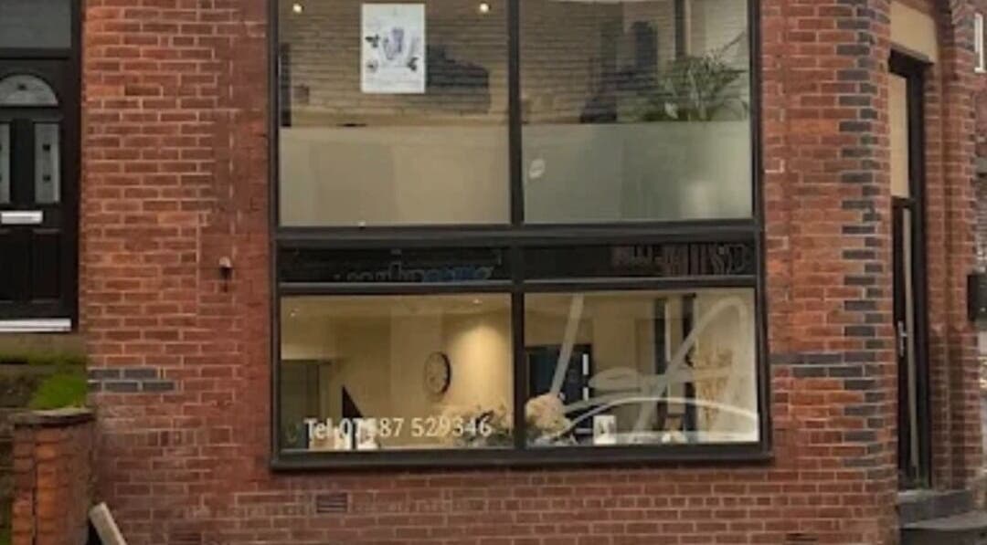 Front facade of The Toni Touch beauty salon in Bolton, England, GB with large windows and brick exterior.