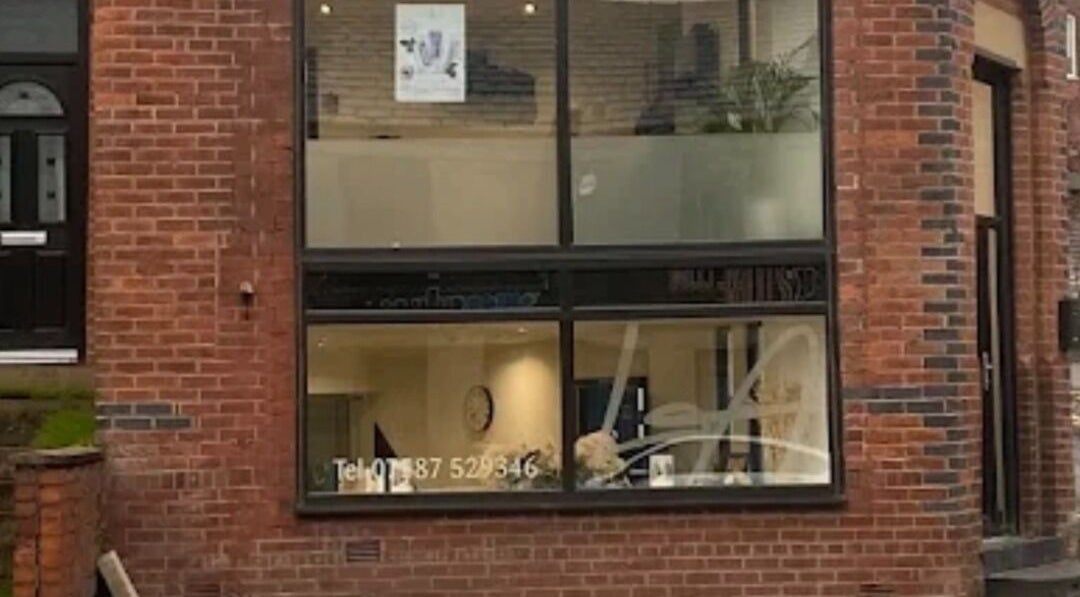 Front facade of The Toni Touch beauty salon in Bolton, England, GB with large windows and brick exterior.