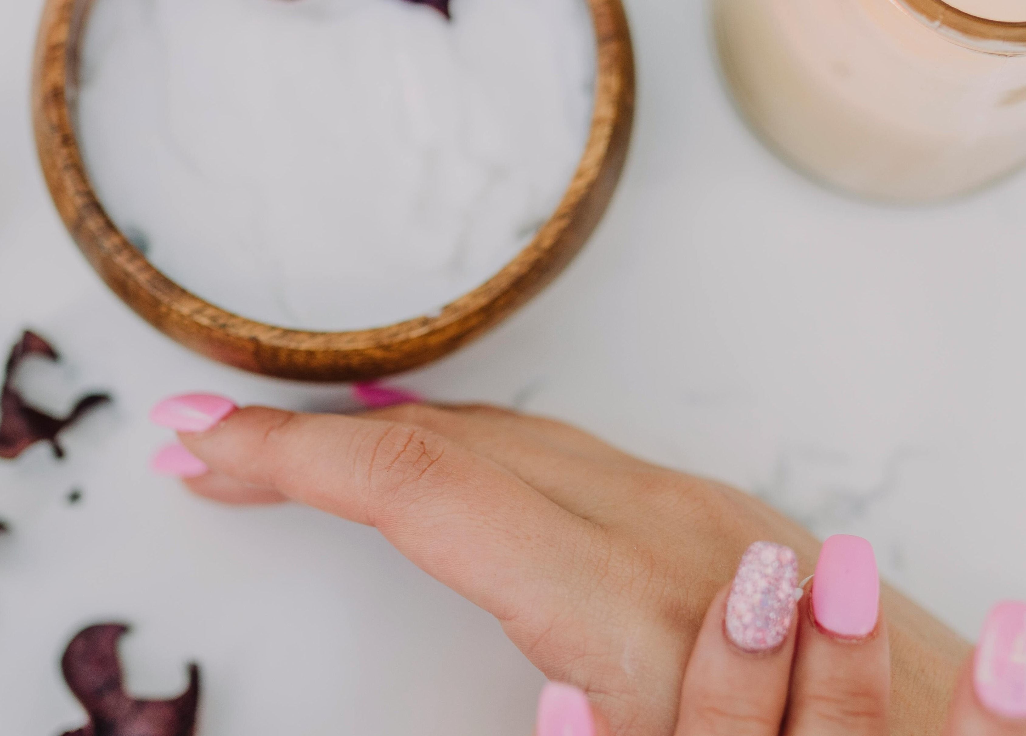 Manicura rosa en Luxotio, Barcelona, Catalunya, ES, junto a crema y flores decorativas.